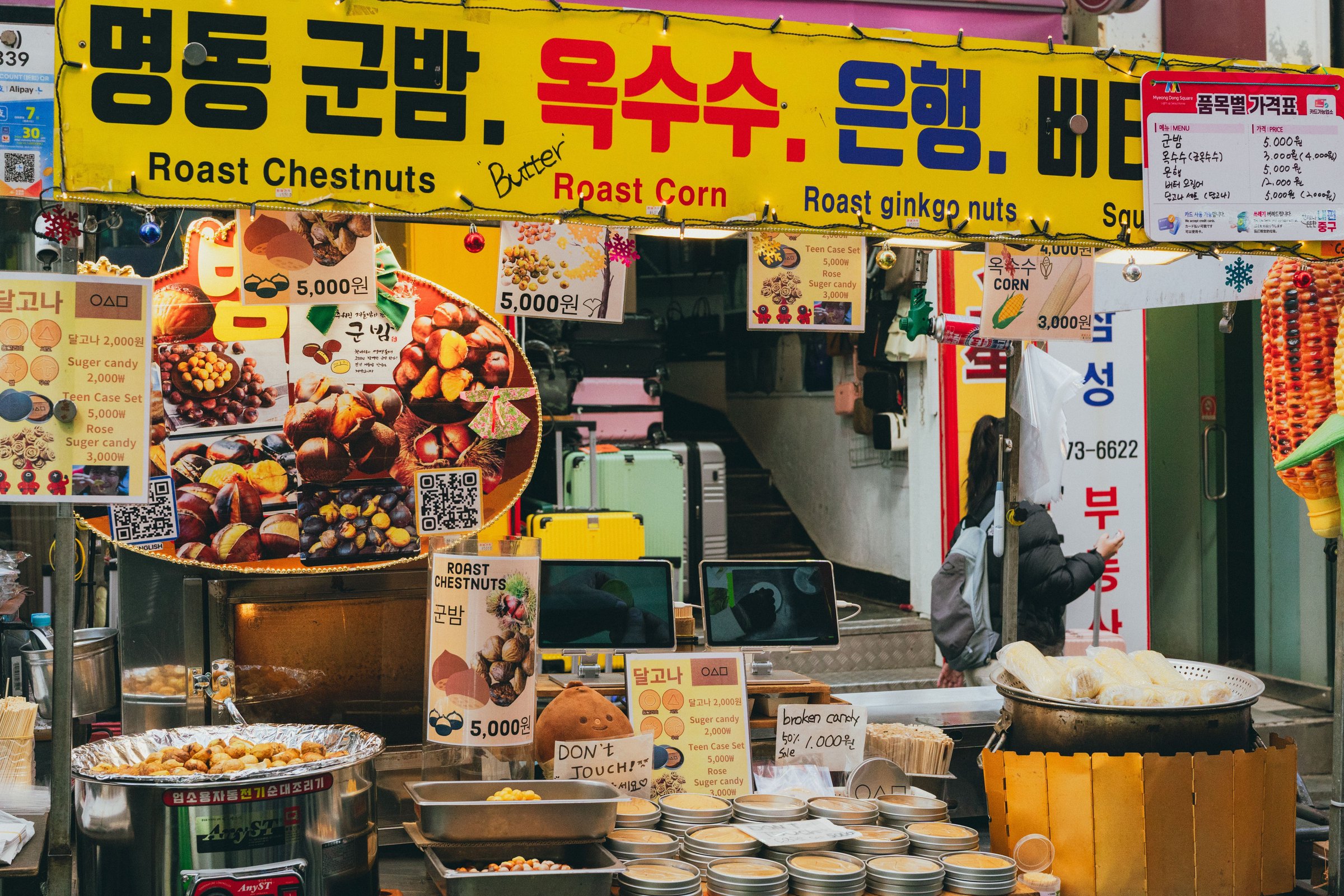 Lapak jajanan kaki lima kastanye panggang khas Myeongdong dengan papan kuning cerah
