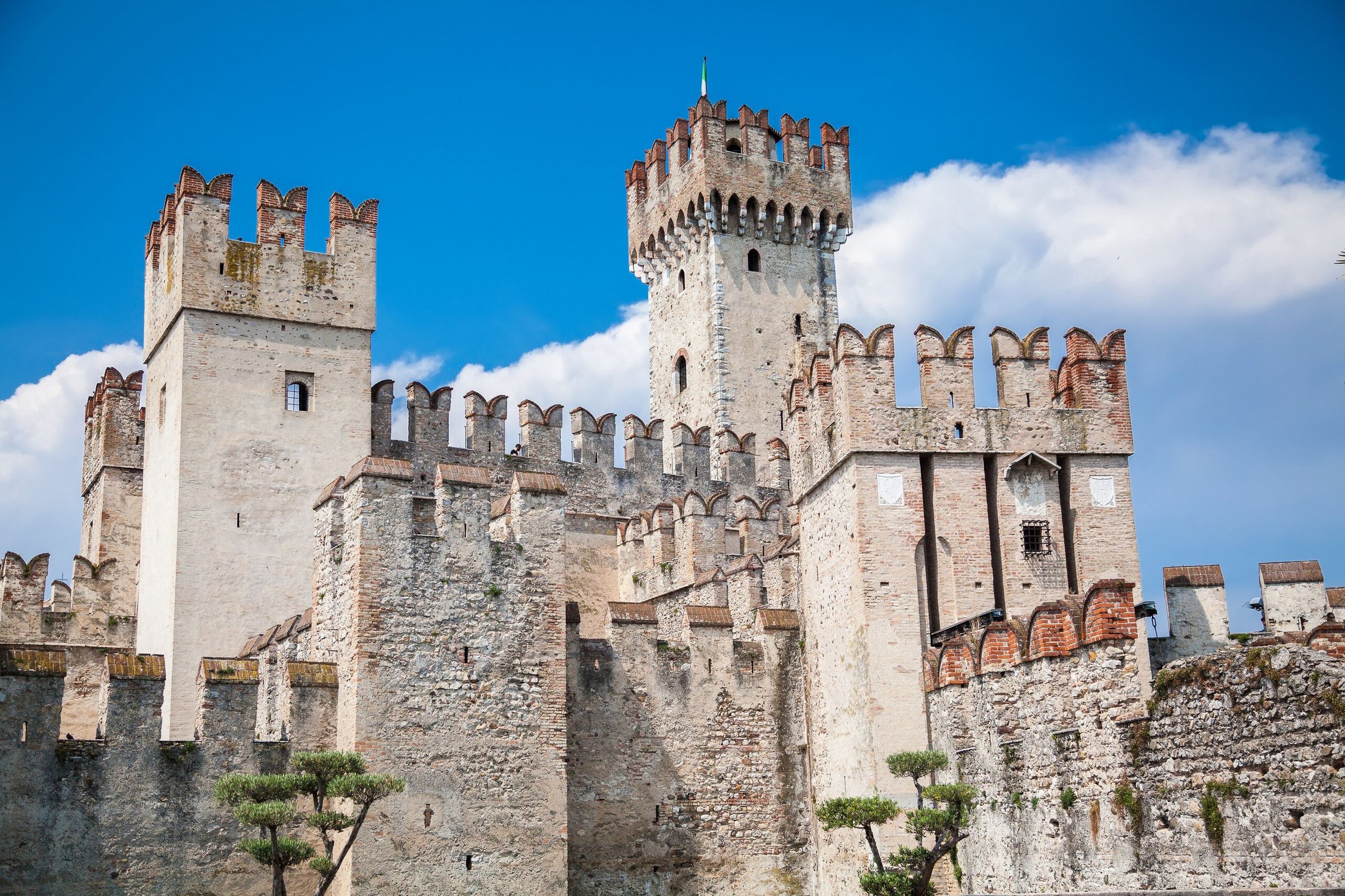 Menara Kastil Scaligero di Sirmione dengan awan putih di langit biru.