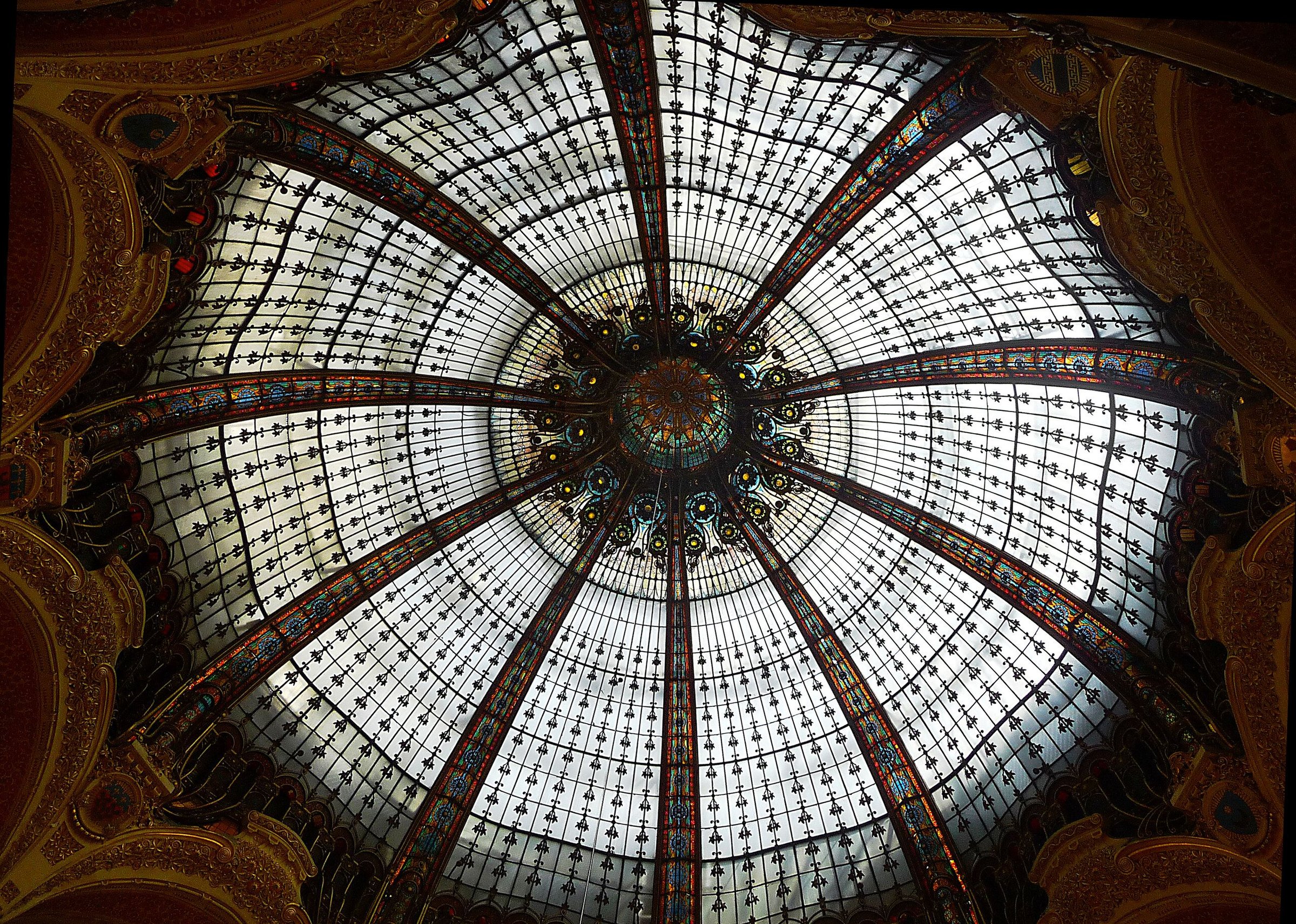 Kubah kaca patri di dalam pusat belanja Galeries Lafayette, Paris, dilihat dari bawah.