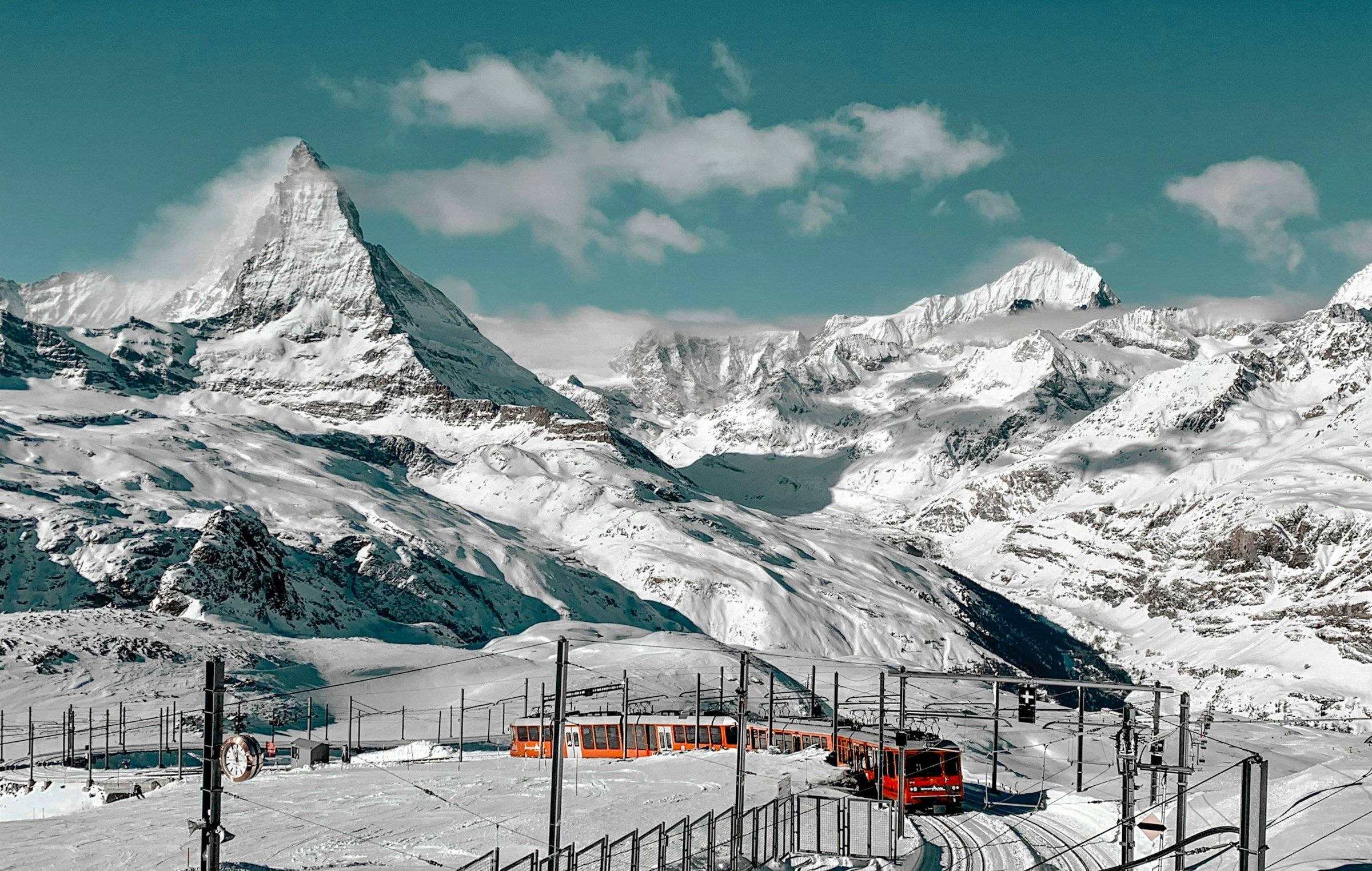 Puncak Matterhorn bersalju di Pegunungan Alpen Swiss dengan kereta Gornergrat merah melintas di Zermatt, Swiss