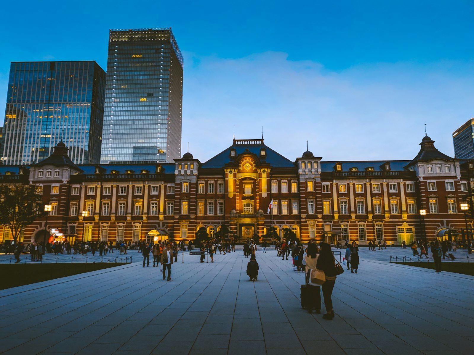 Bangunan megah Stasiun Tokyo Marunouchi di senja hari, dengan latar belakang gedung pencakar langit.
