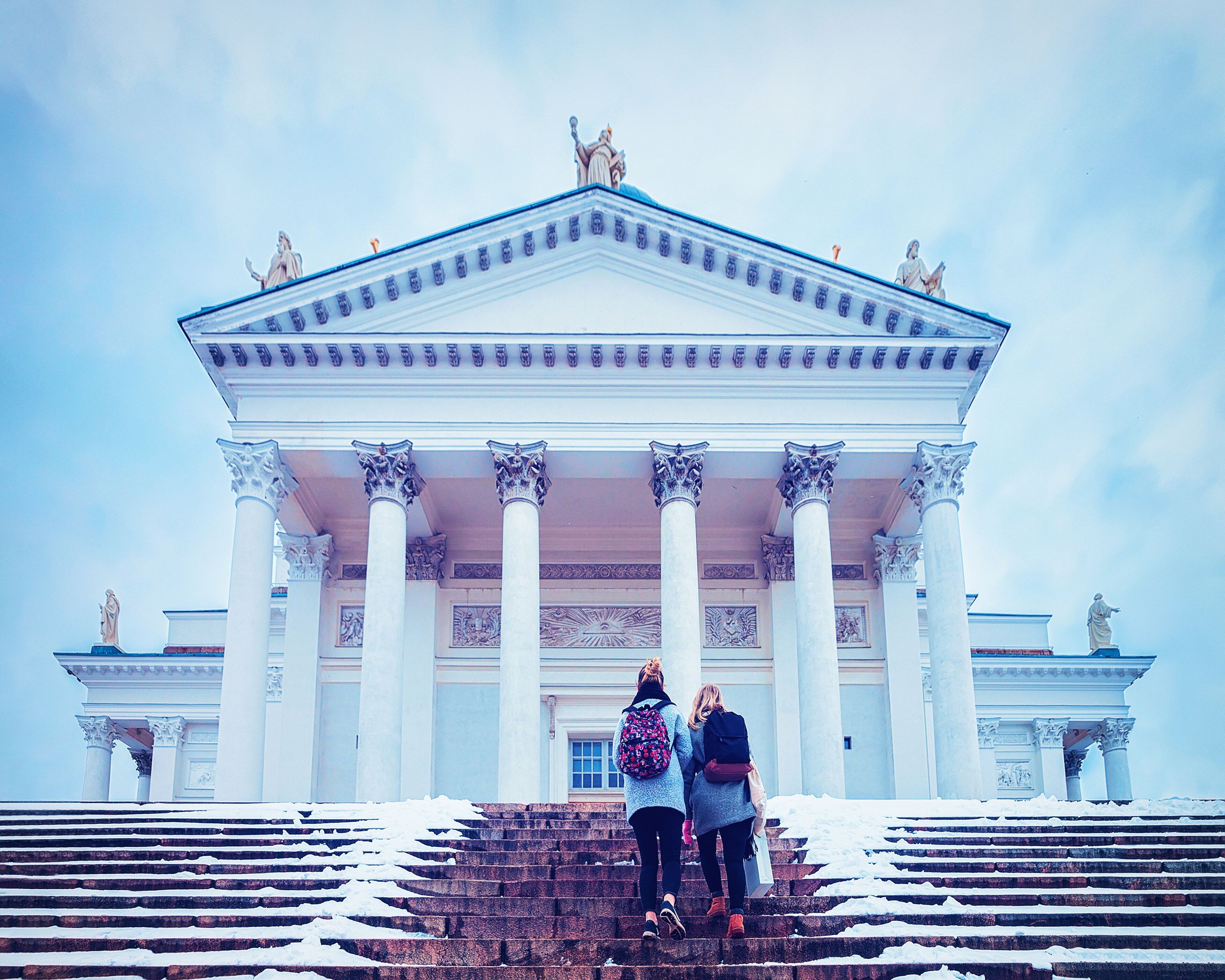 Dua wisatawan menaiki tangga Katedral Helsinki yang berselimut salju