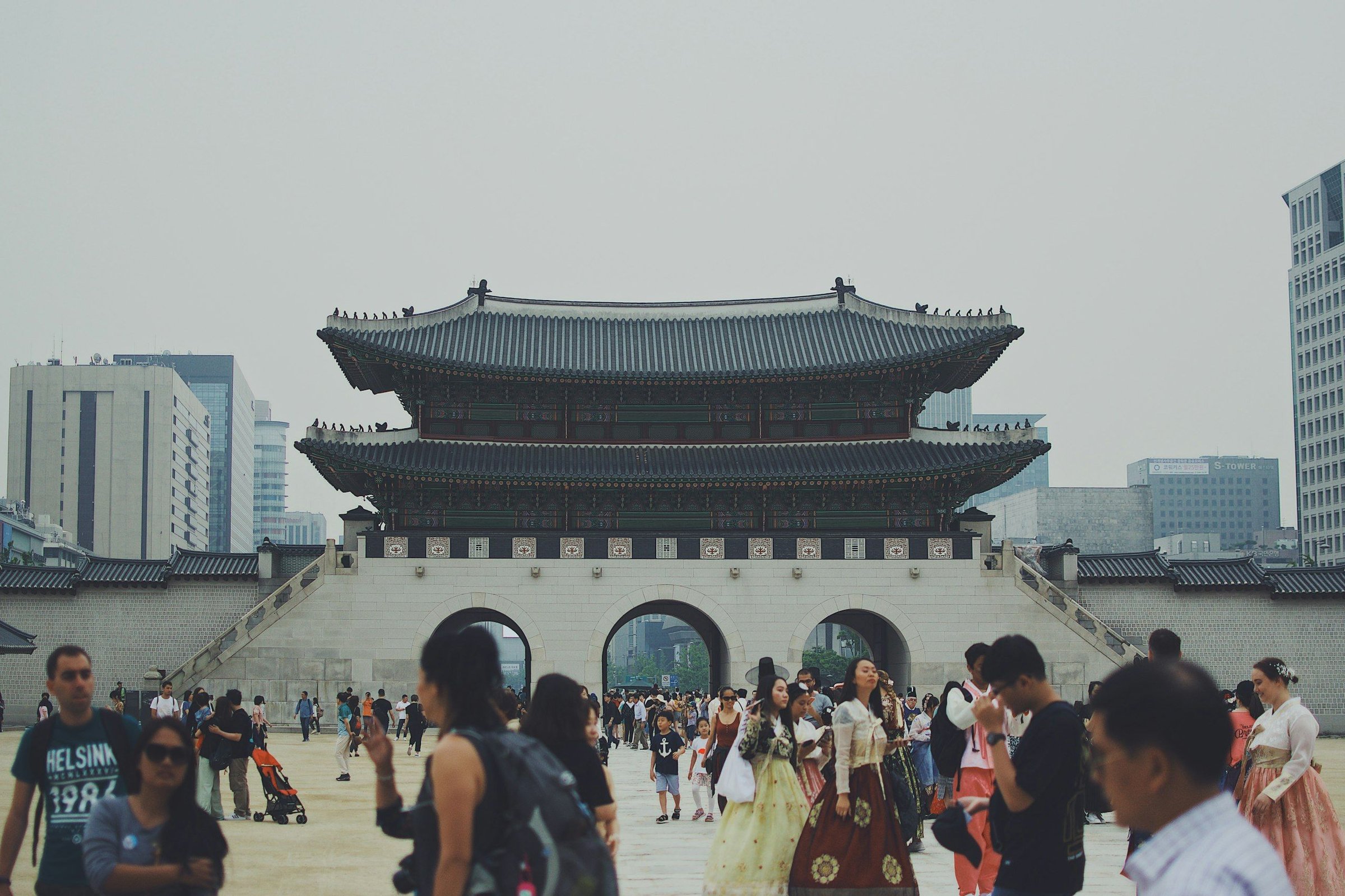 Gerbang Gwanghwamun Istana Gyeongbokgung di Seoul dengan pengunjung berhanbok dan latar gedung kota