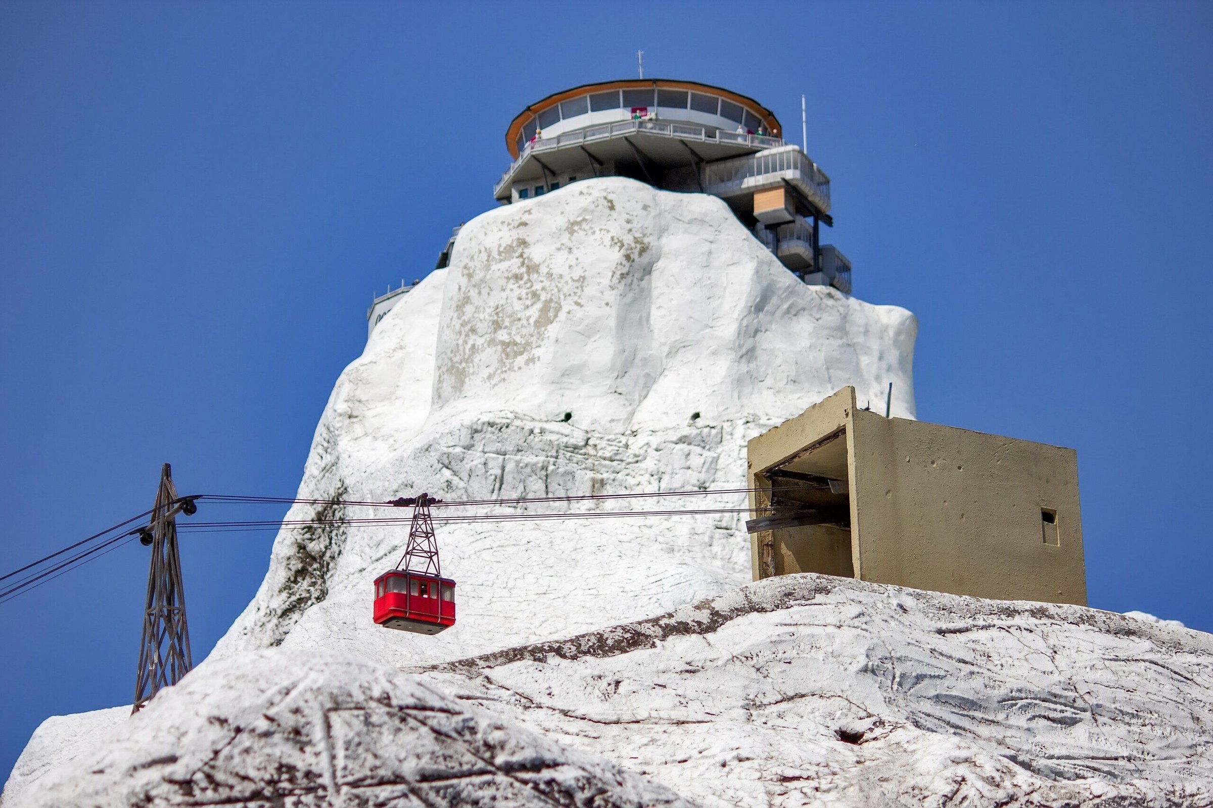 Kereta gantung merah menuju Piz Gloria di puncak Schilthorn, dengan salju di batu putih.
