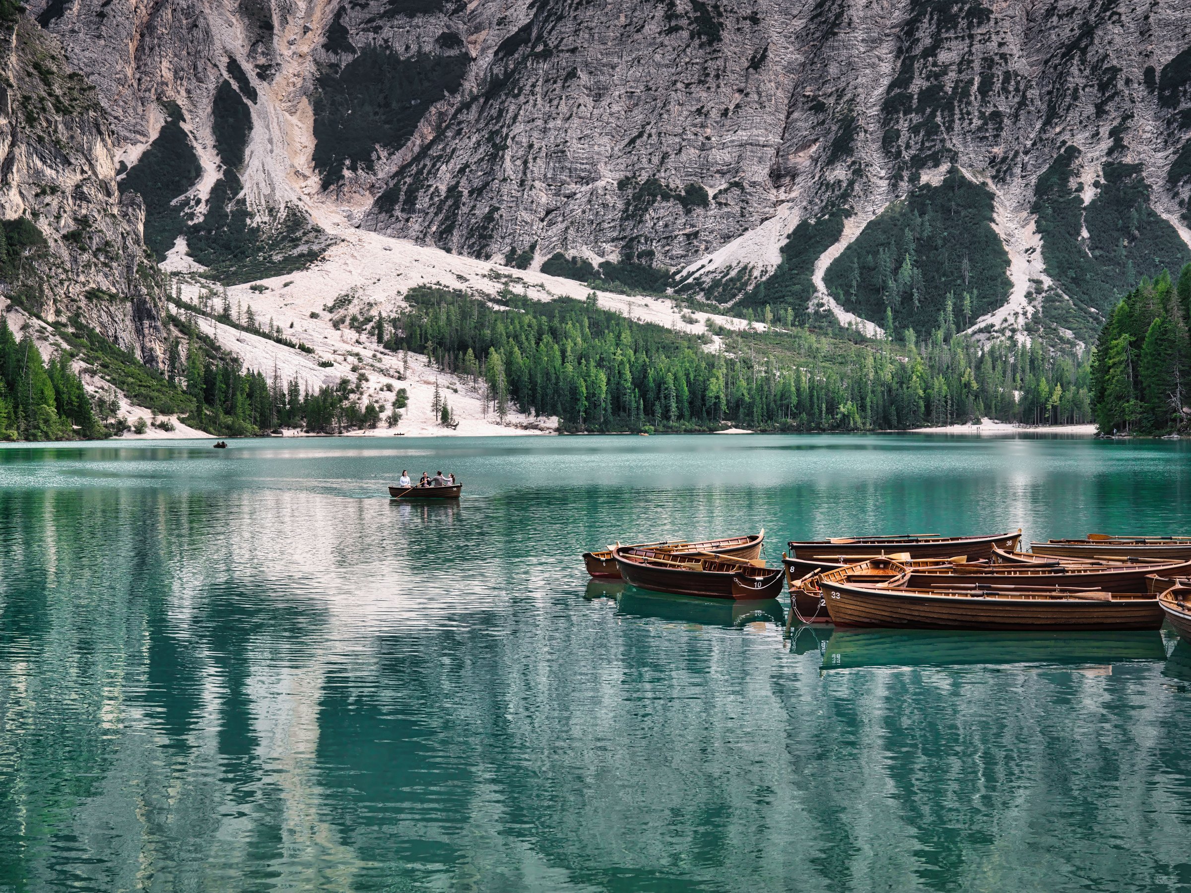 Lake Braies dengan air biru jernih dan perahu kayu di kaki tebing Dolomites