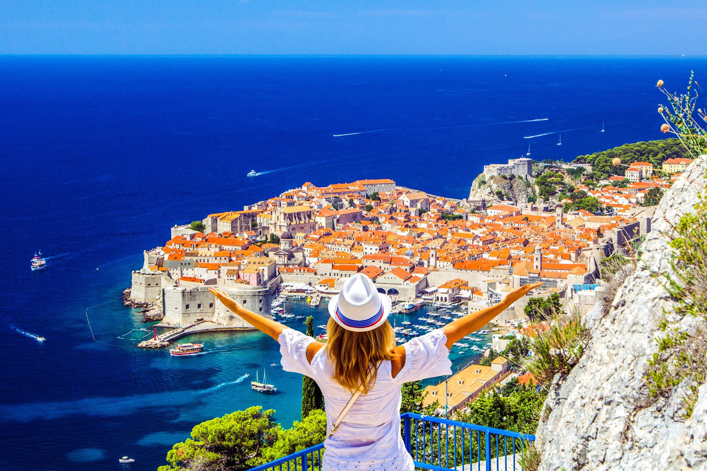 Wisatawan membentangkan tangan menghadap kota tua Dubrovnik dan Laut Adriatik
