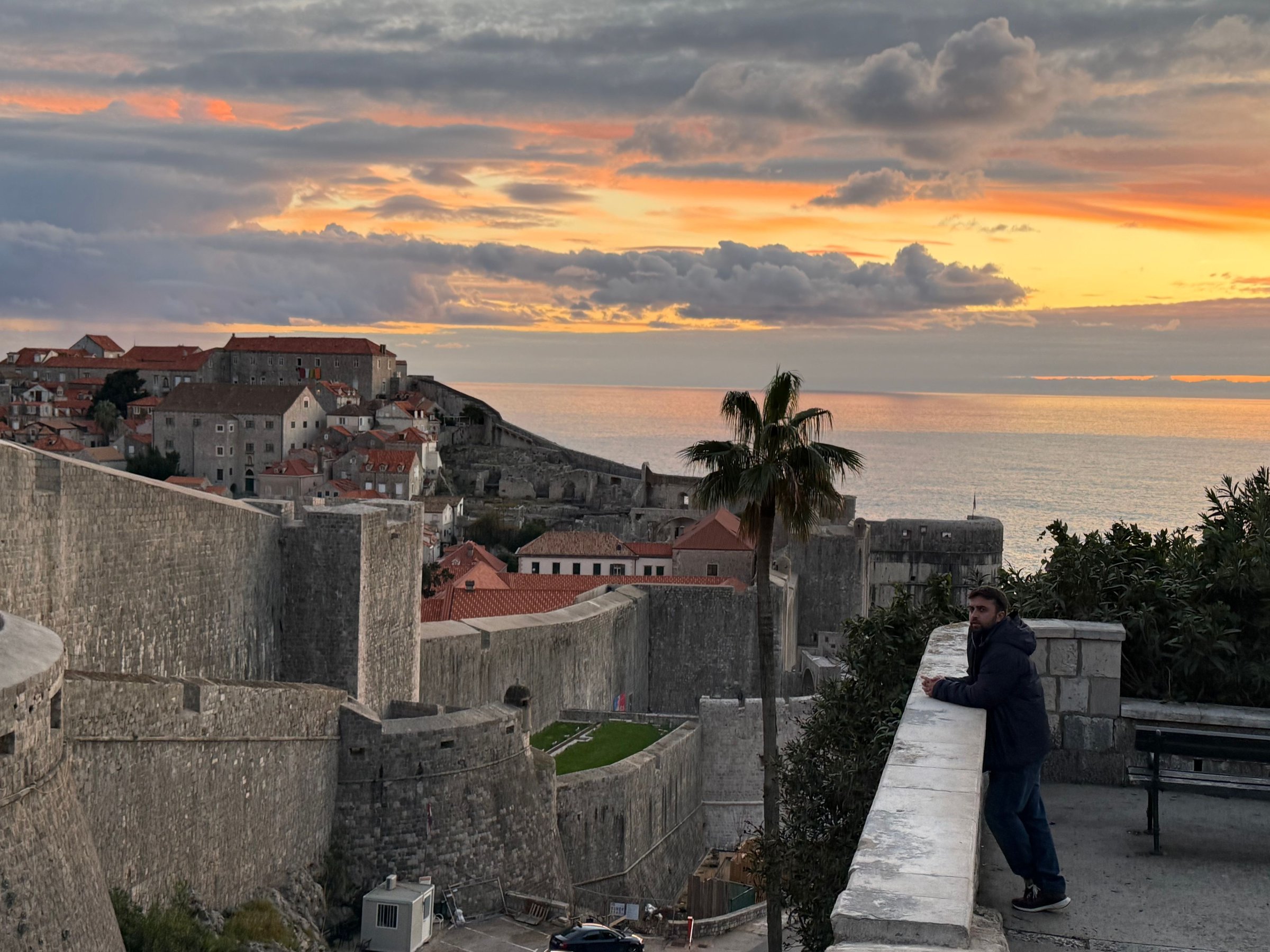 Tembok kota Dubrovnik saat senja dengan laut Adriatik di belakangnya.
