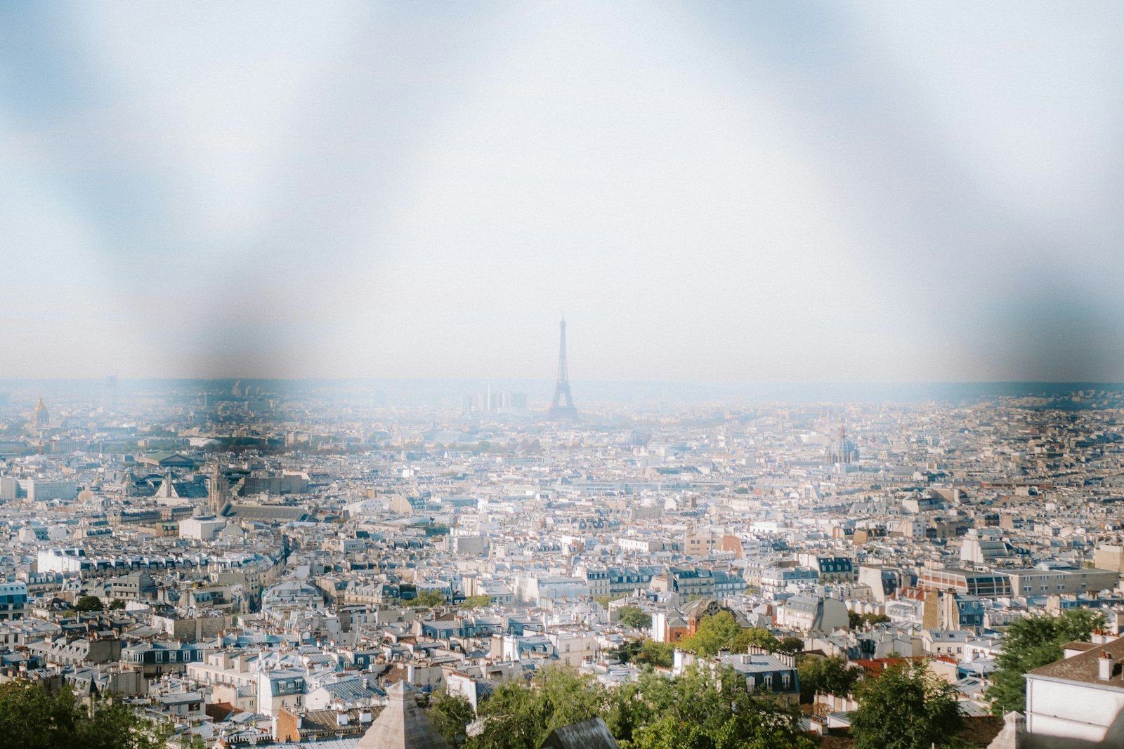 Pemandangan luas kota Paris dari ketinggian, dengan Menara Eiffel di kejauhan.