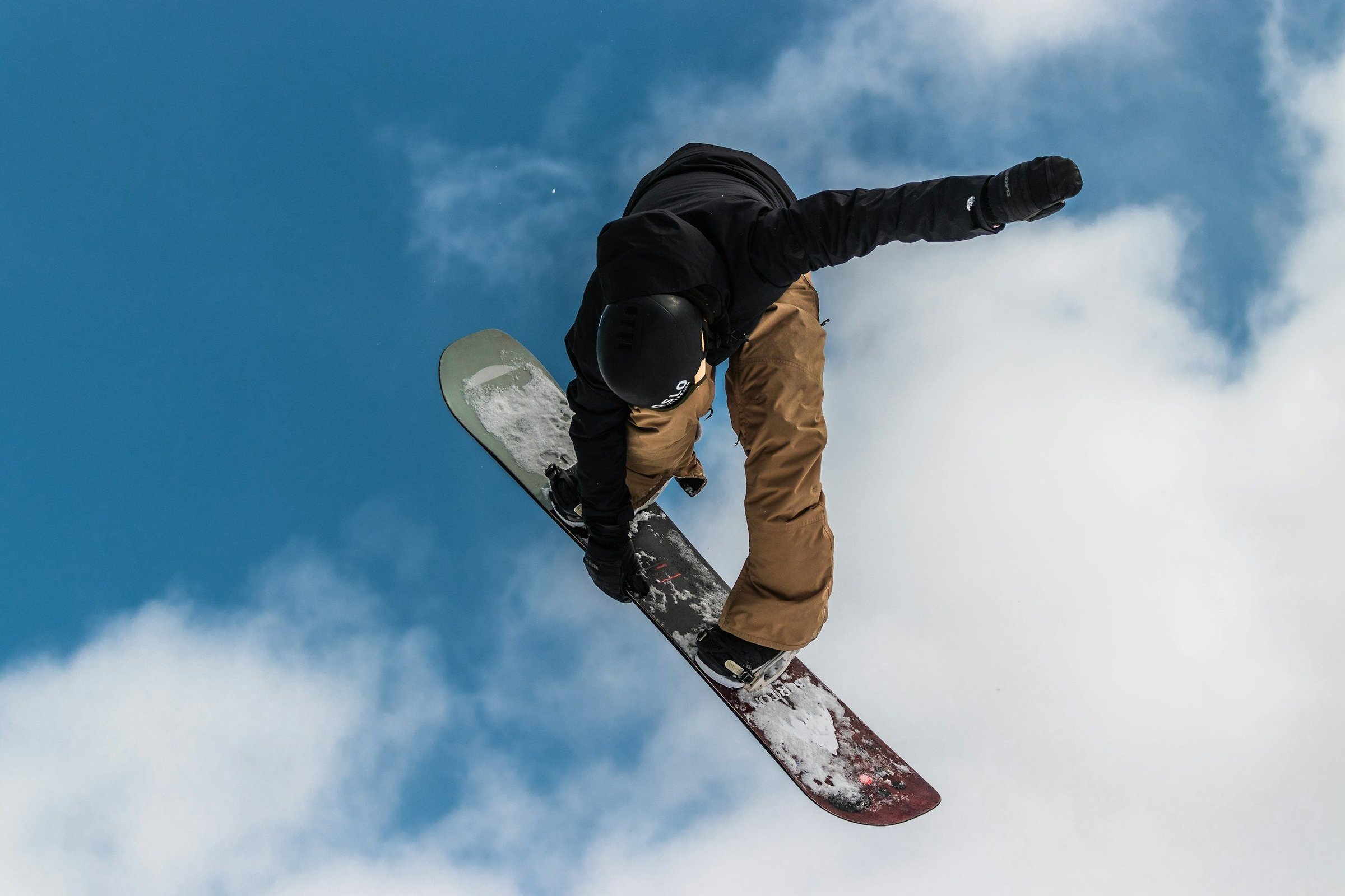 Snowboarder melompat di udara dengan latar langit biru, olahraga salju musim dingin