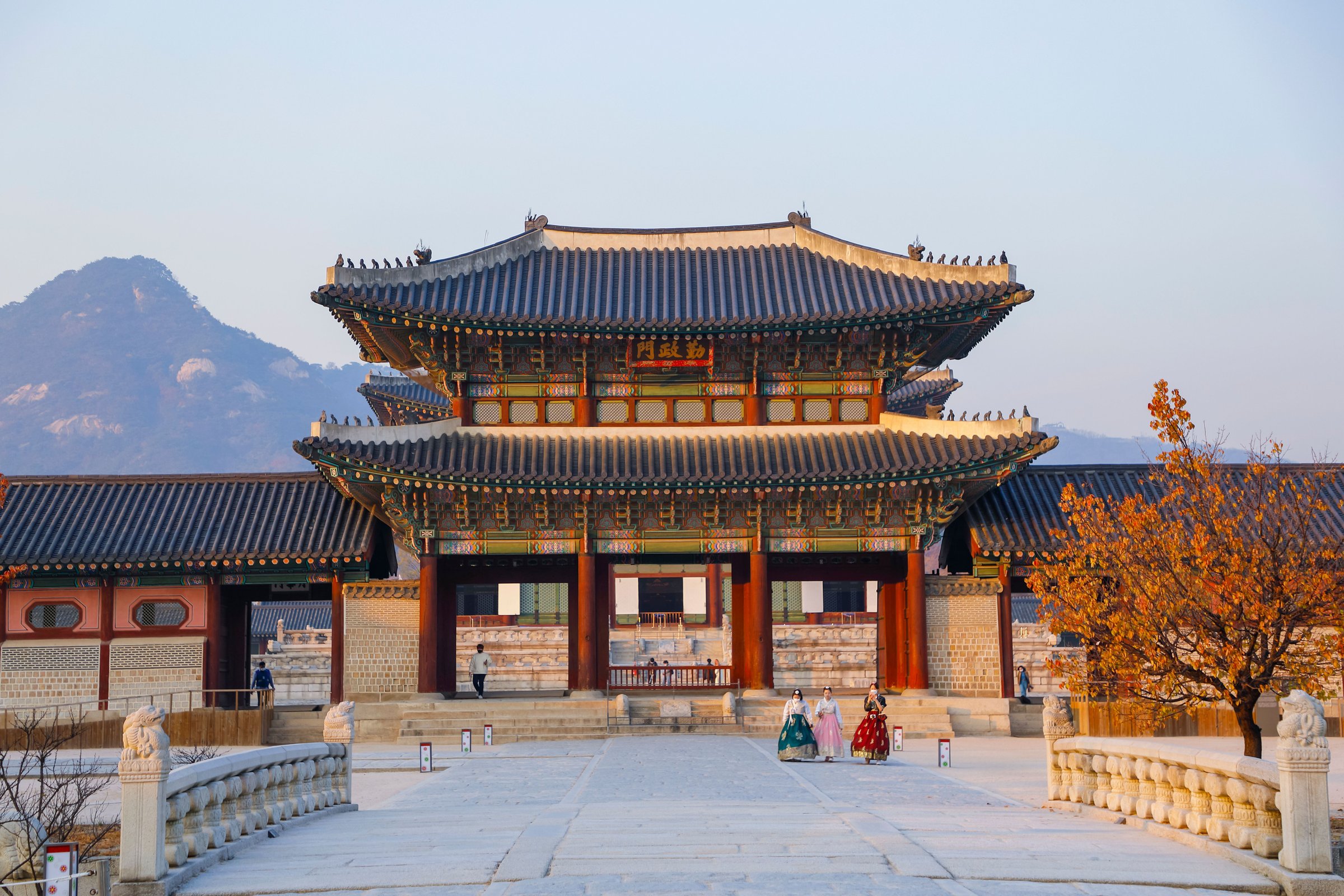 Gerbang Istana Gyeongbokgung Seoul bermandi cahaya keemasan sore dengan latar gunung