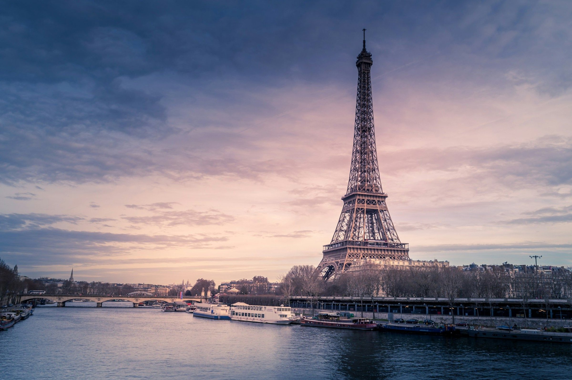 Menara Eiffel Paris menjulang di tepi Sungai Seine saat langit senja merah muda keunguan