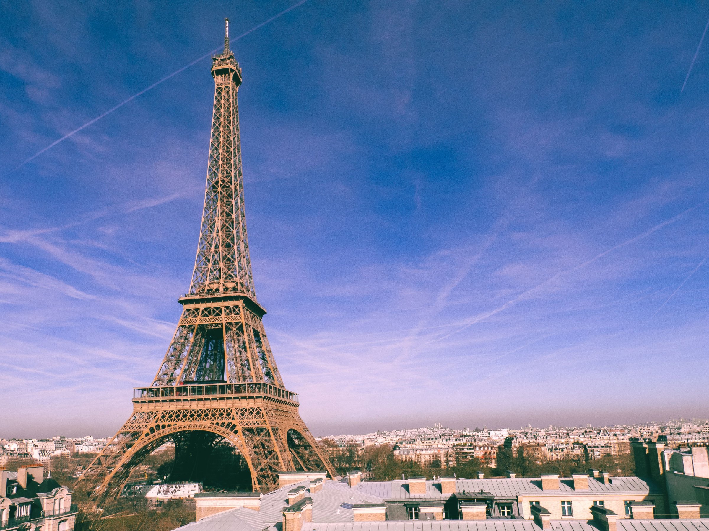 Menara Eiffel Paris menjulang penuh dari kaki hingga puncak dengan langit biru cerah