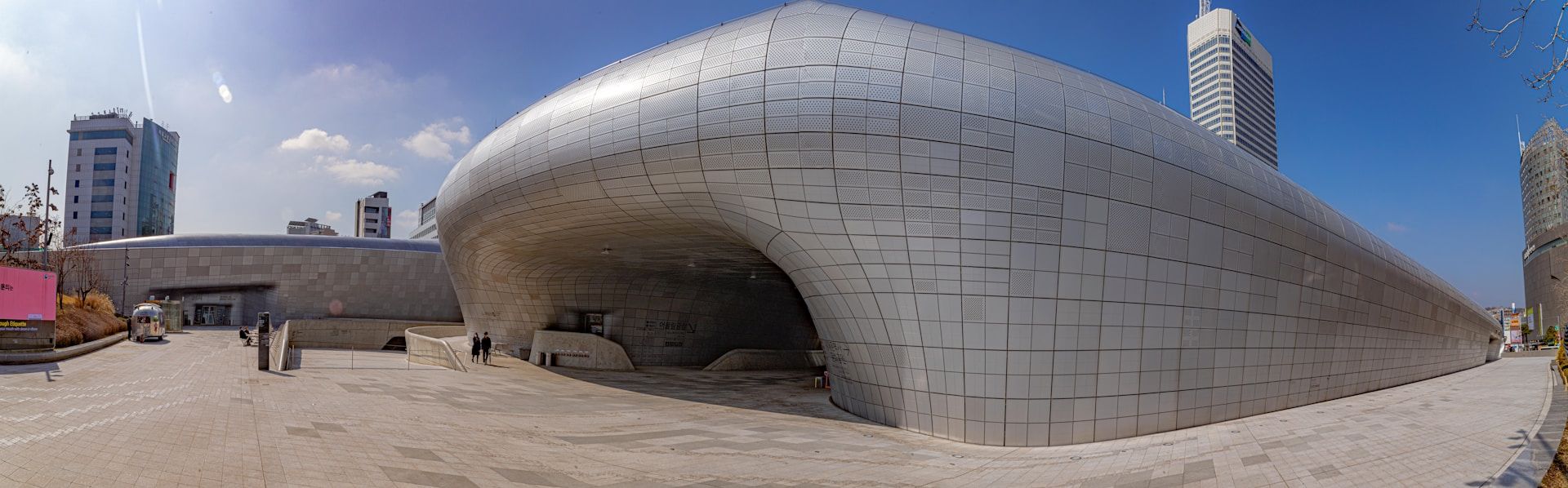 Arsitektur futuristik Dongdaemun Design Plaza Zaha Hadid di Seoul dengan dinding aluminium melengkung dan cahaya malam yang berkilau