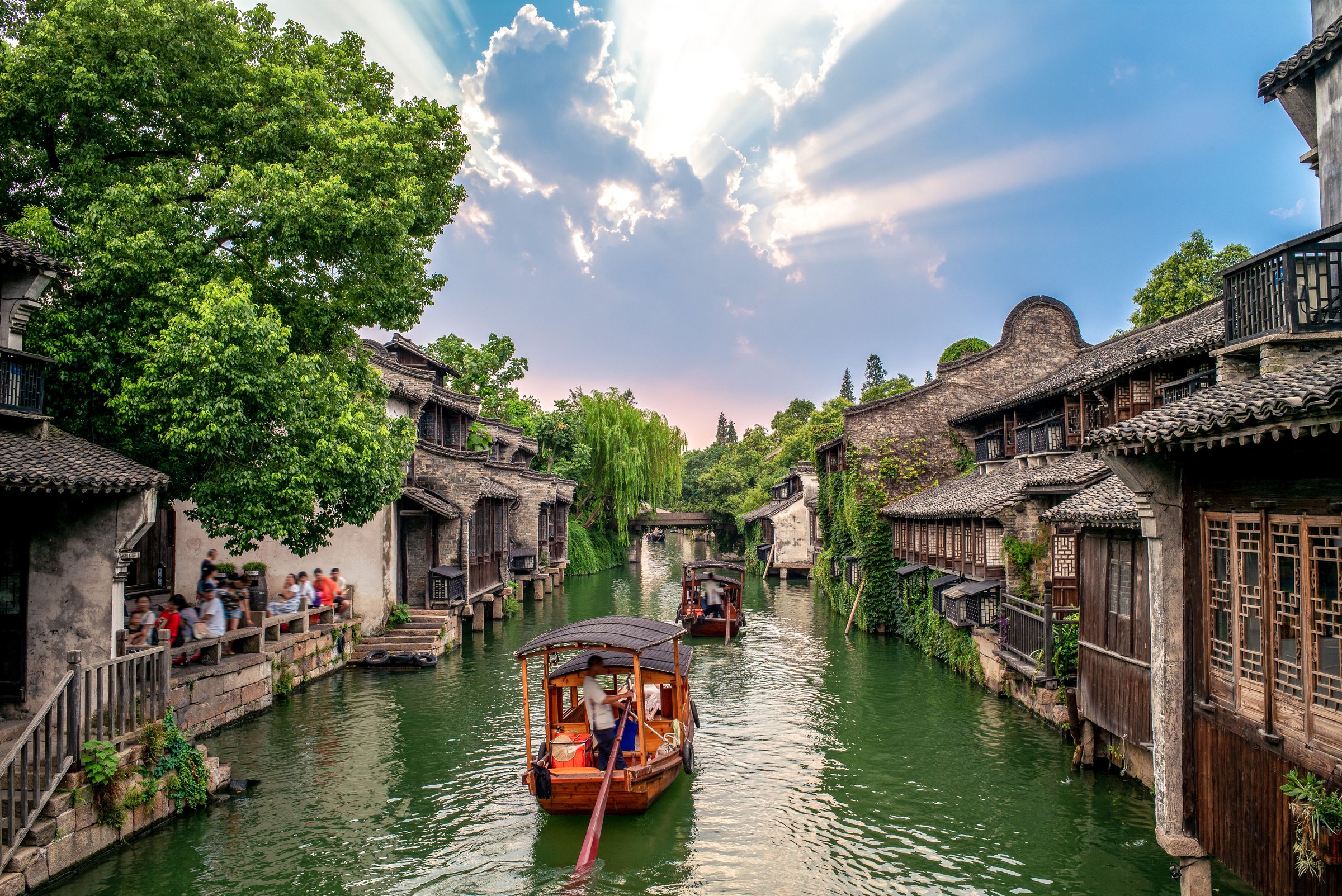 Perahu kayu menyusuri kanal Wuzhen di antara rumah-rumah kayu tua