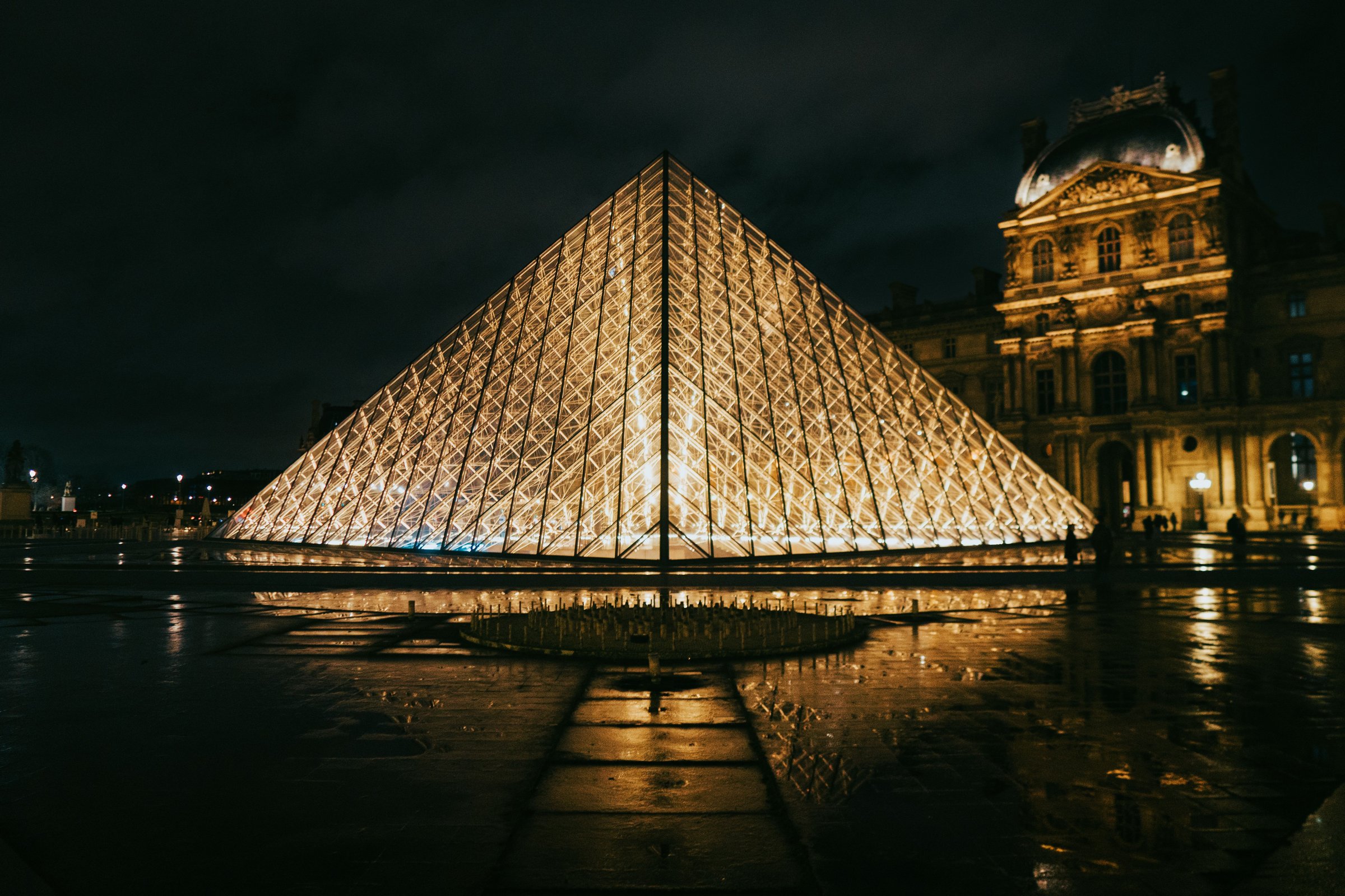 Piramida kaca Louvre menyala keemasan di malam hari Paris