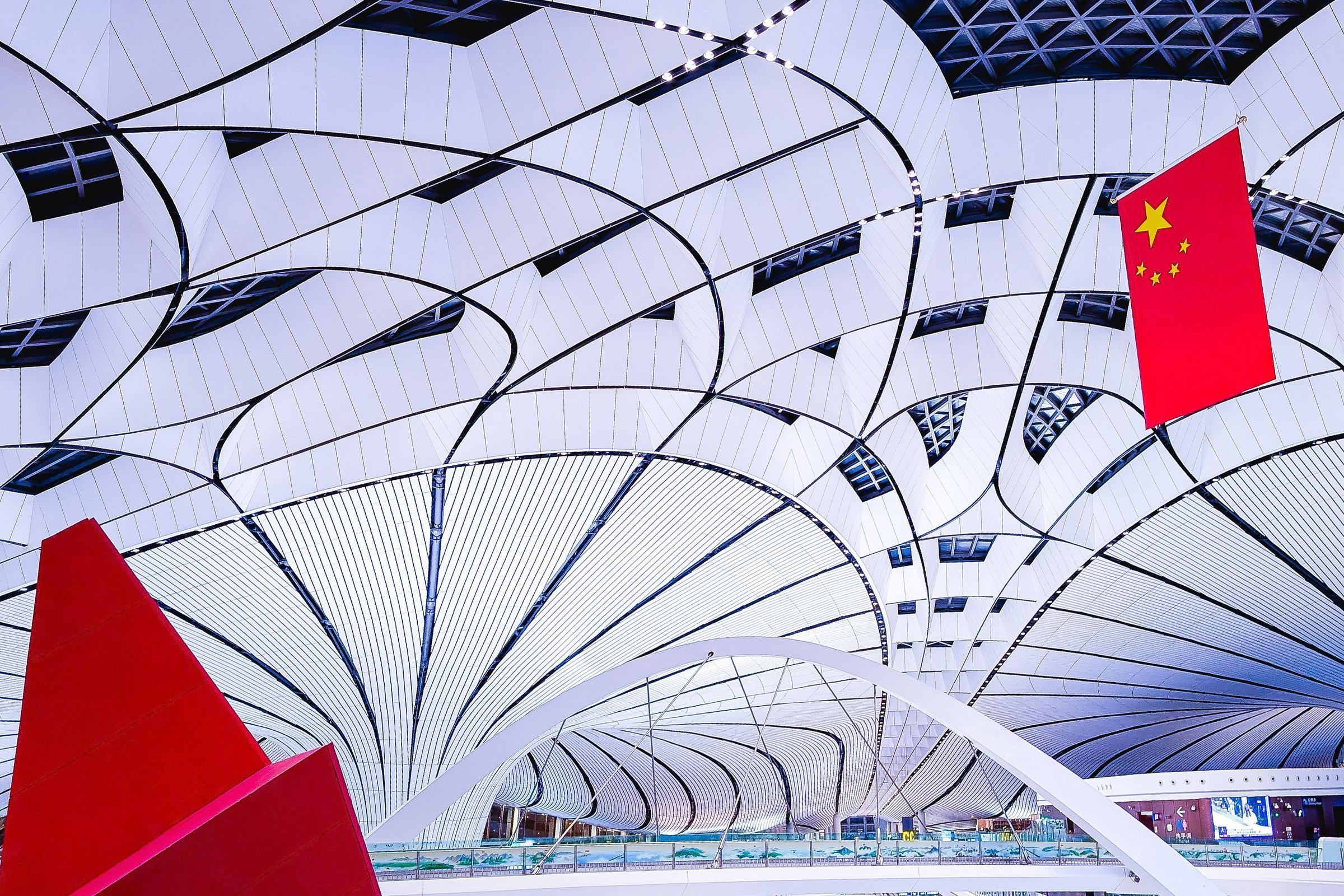 Interior futuristik Bandara Daxing Beijing dengan bendera China berkibar