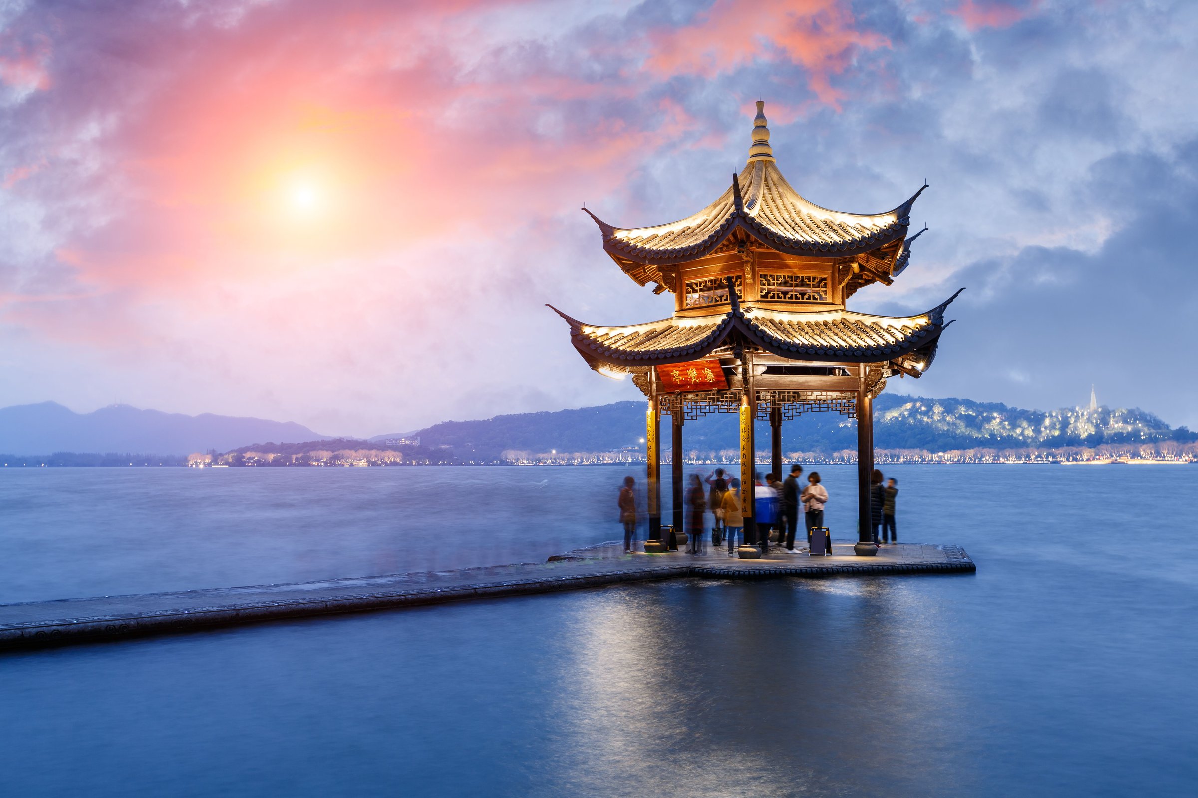Paviliun klasik di tepi West Lake Hangzhou saat senja dengan langit merah muda