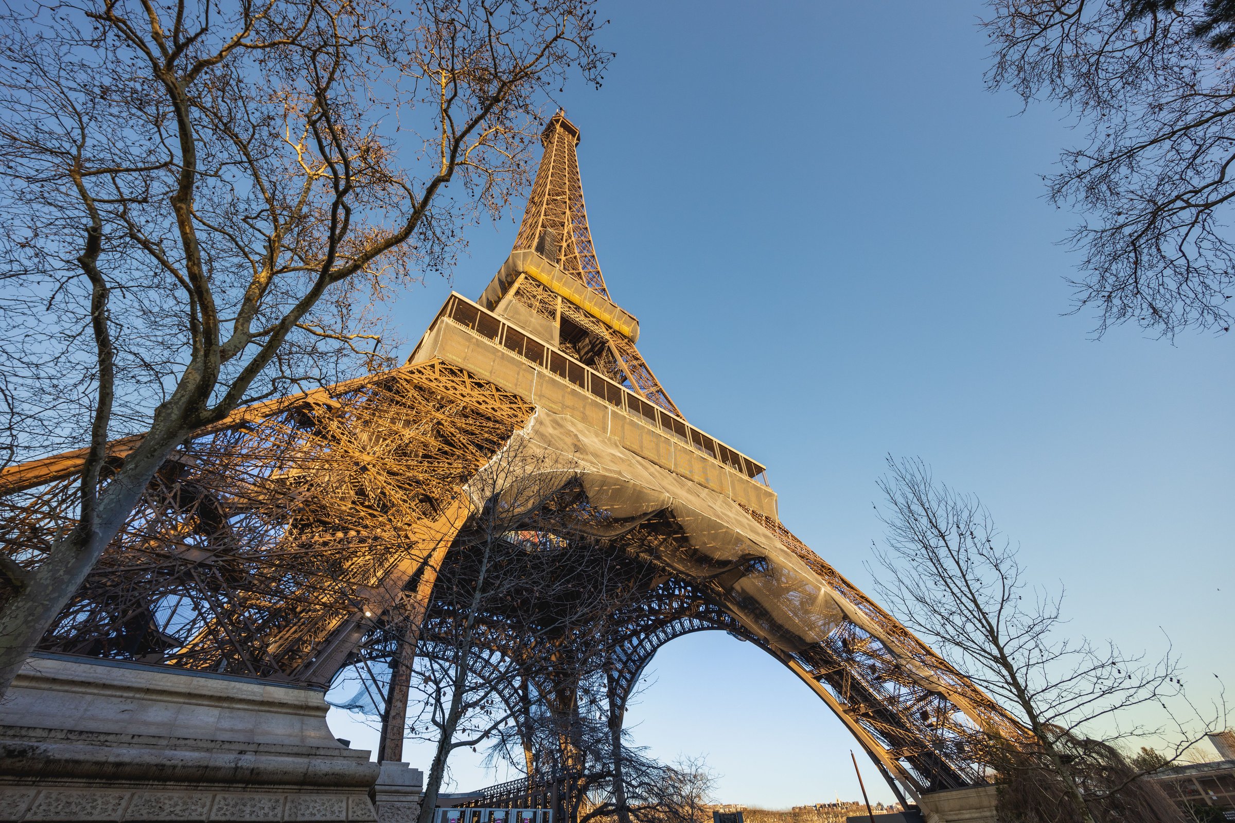 Menara Eiffel terlihat dari bawah bermandikan cahaya keemasan senja langit biru cerah