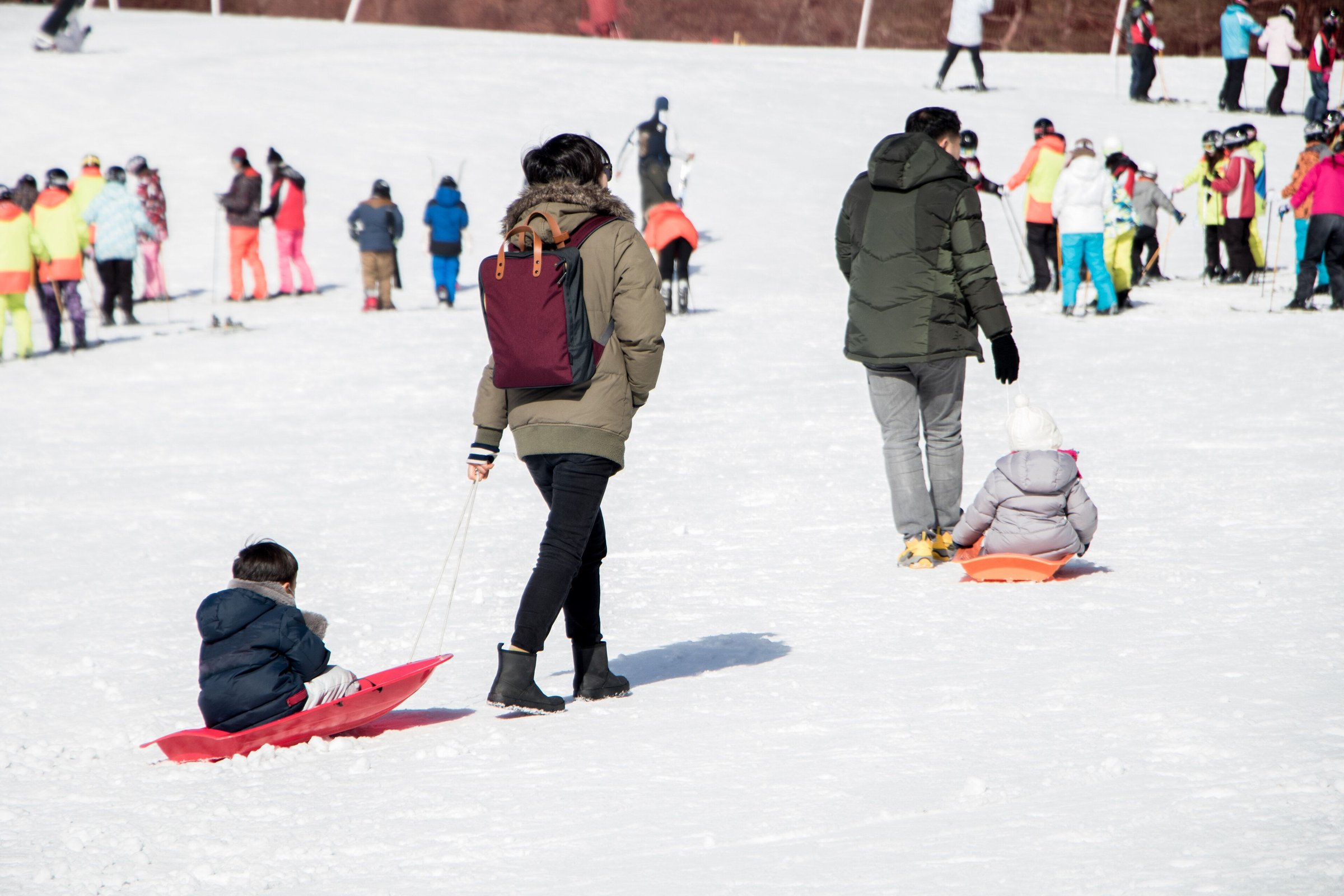 Keluarga bermain seluncur salju dan berjalan di lereng resor ski Korea yang cerah