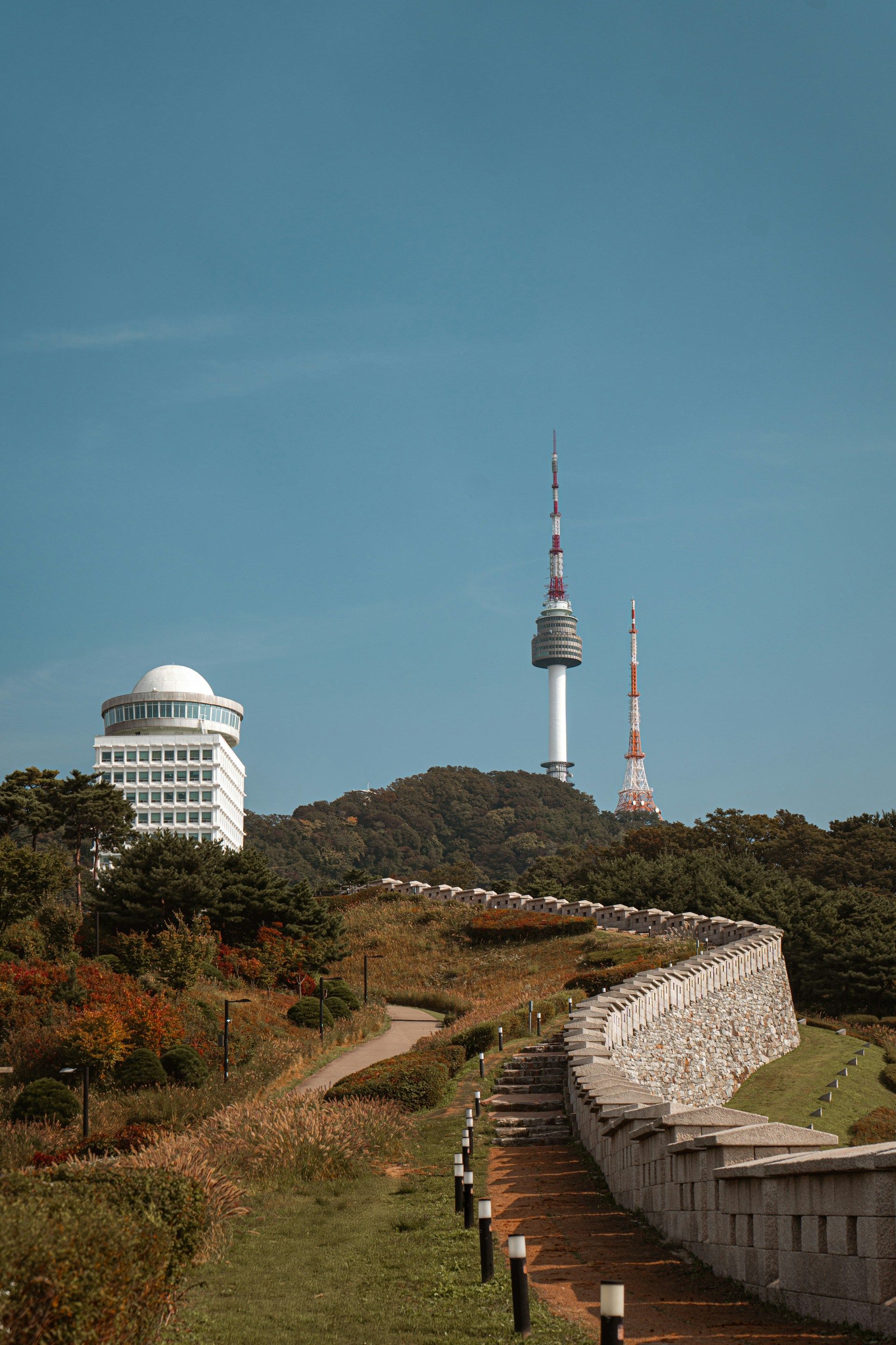 N Seoul Tower berdiri di puncak Namsan dengan pemandangan kota Seoul yang membentang di bawahnya pada sore hari
