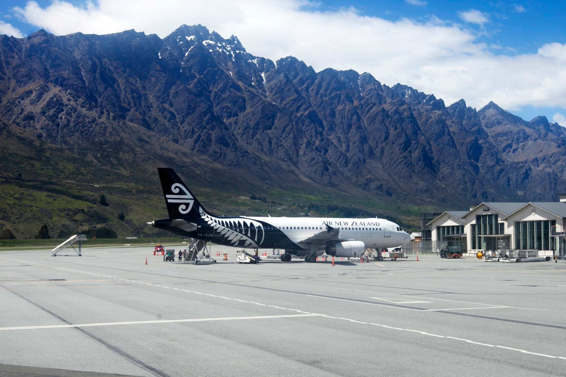 Pesawat Air New Zealand terparkir di Bandara Queenstown dengan latar pegunungan Remarkables