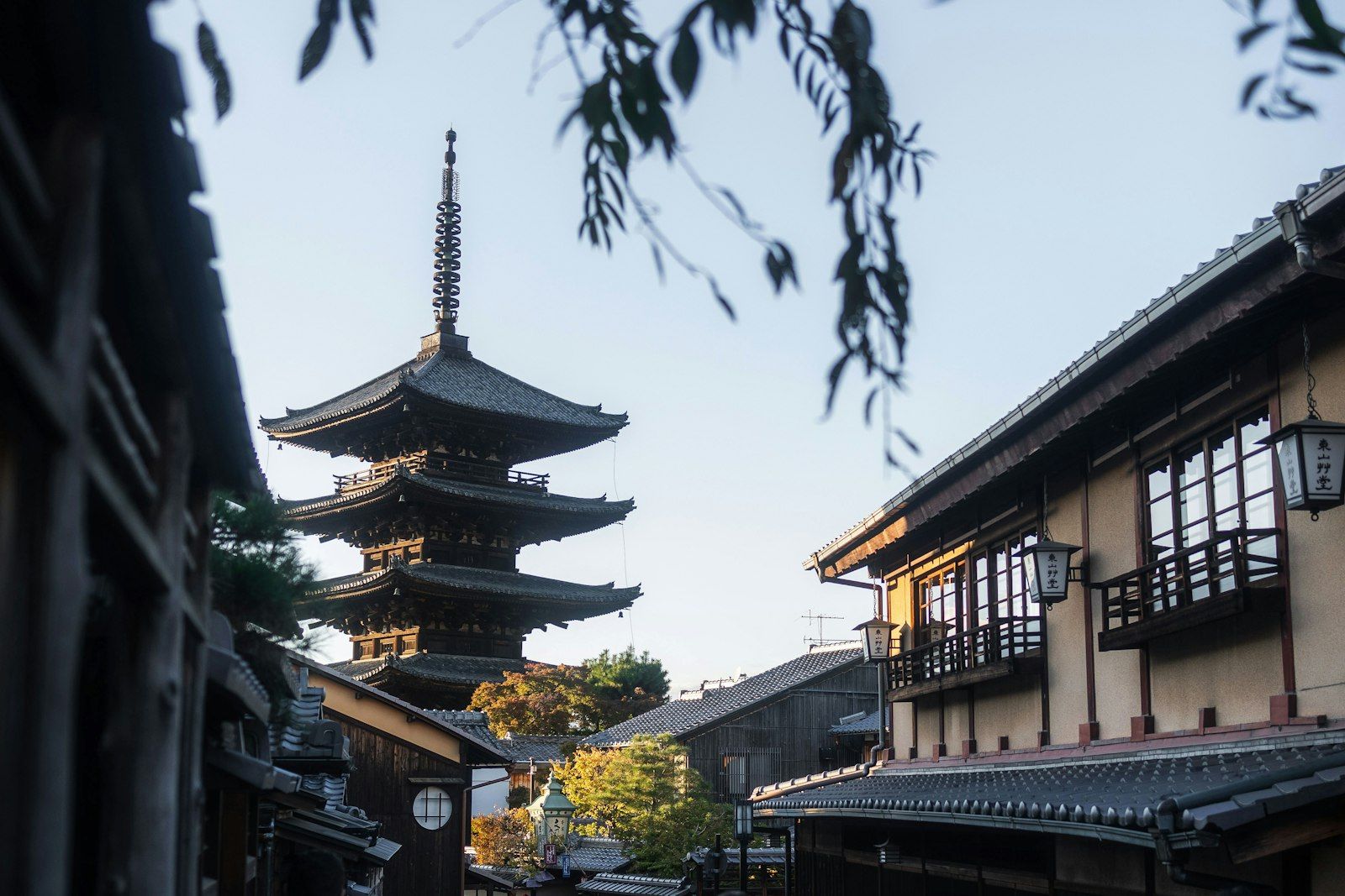 Pagoda kuno lima lantai di antara bangunan tradisional Jepang di bawah langit biru.