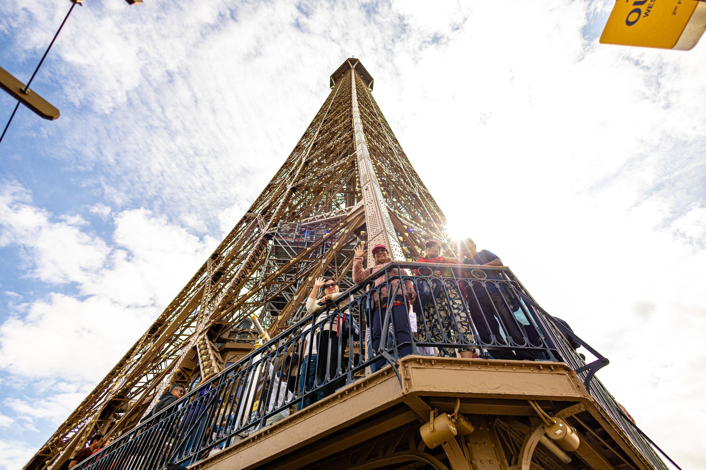 Keluarga Santoso: Foto keluarga di depan Menara Eiffel, background langit Paris cerah pas siang hari.
