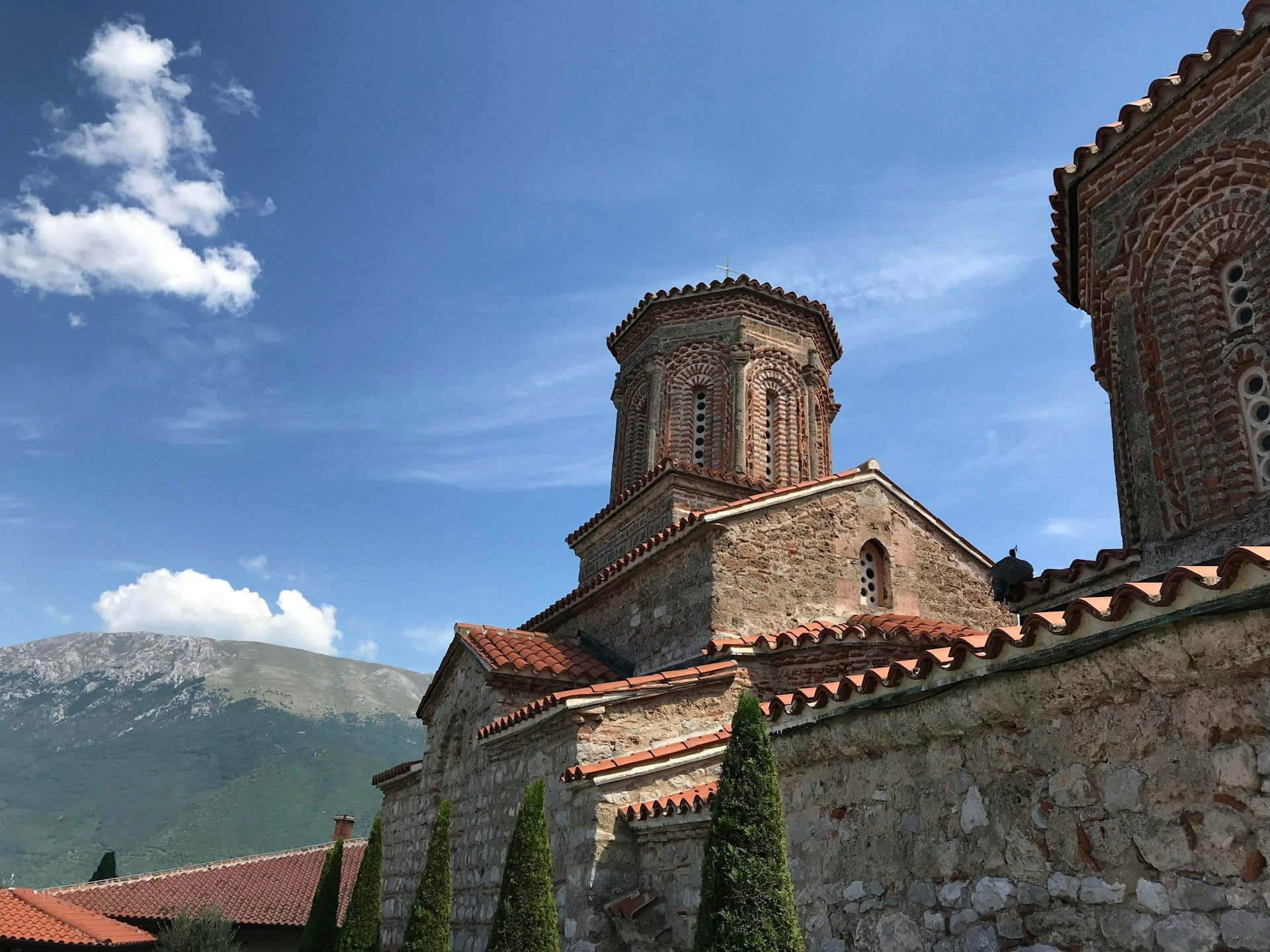 Biara Sveti Naum di tepi Danau Ohrid, menara lonceng Bizantium berkubah dan pohon cemara di halaman batu
