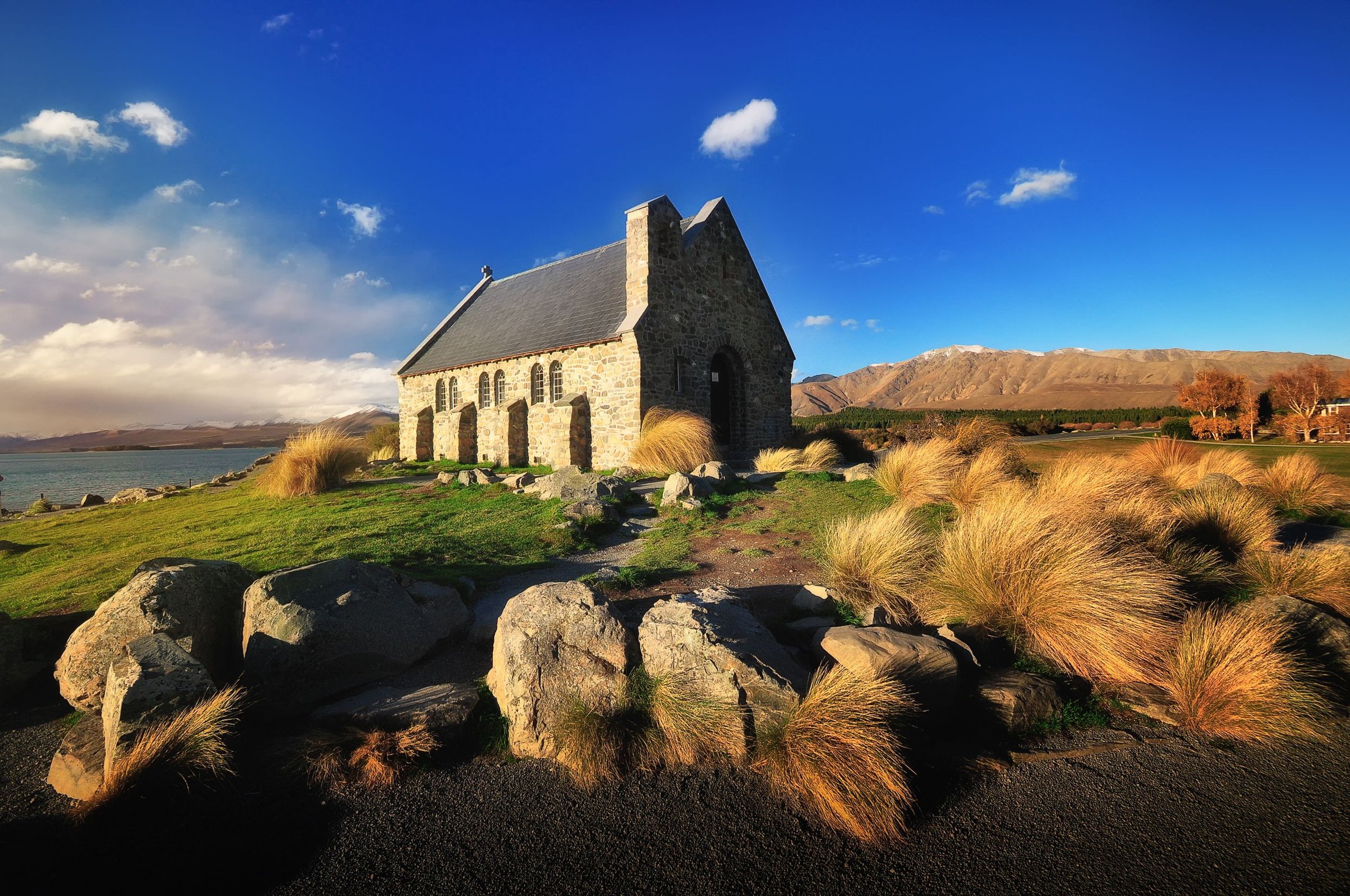 Church of the Good Shepherd dari batu di tepi Lake Tekapo saat hari cerah berlangit biru