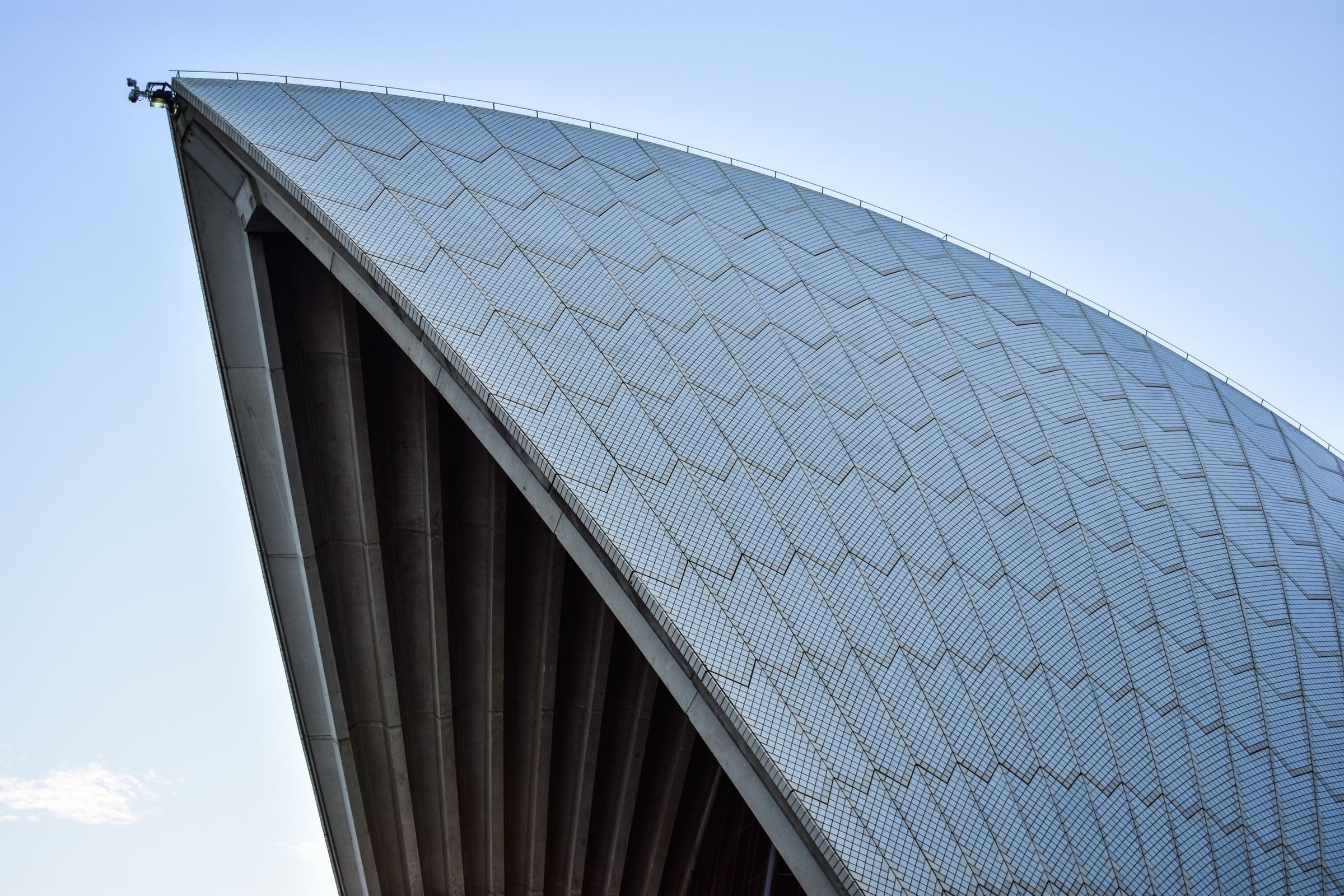 Layar putih Sydney Opera House dari dekat dengan langit biru cerah