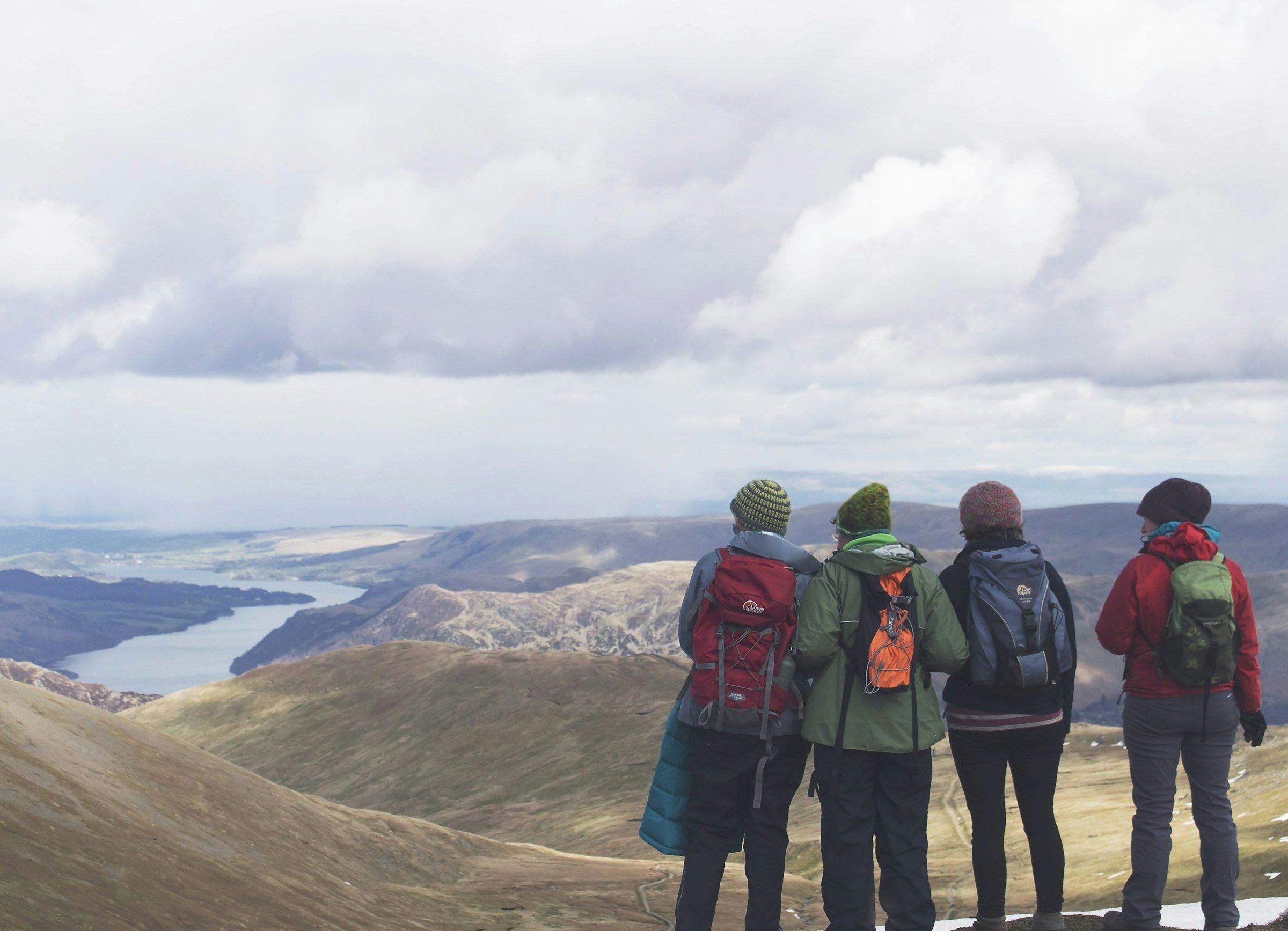 Empat traveler berdiri bersama menikmati pemandangan dari puncak, contoh perjalanan grup kecil