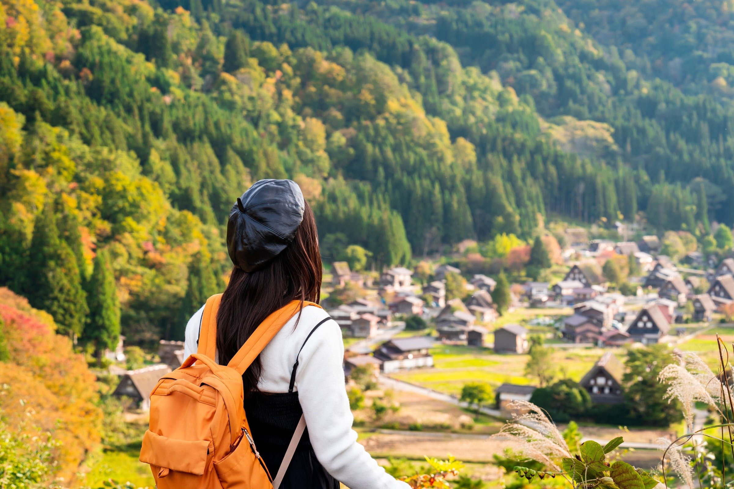 Perempuan memandang desa Shirakawago dengan rumah gassho saat musim gugur
