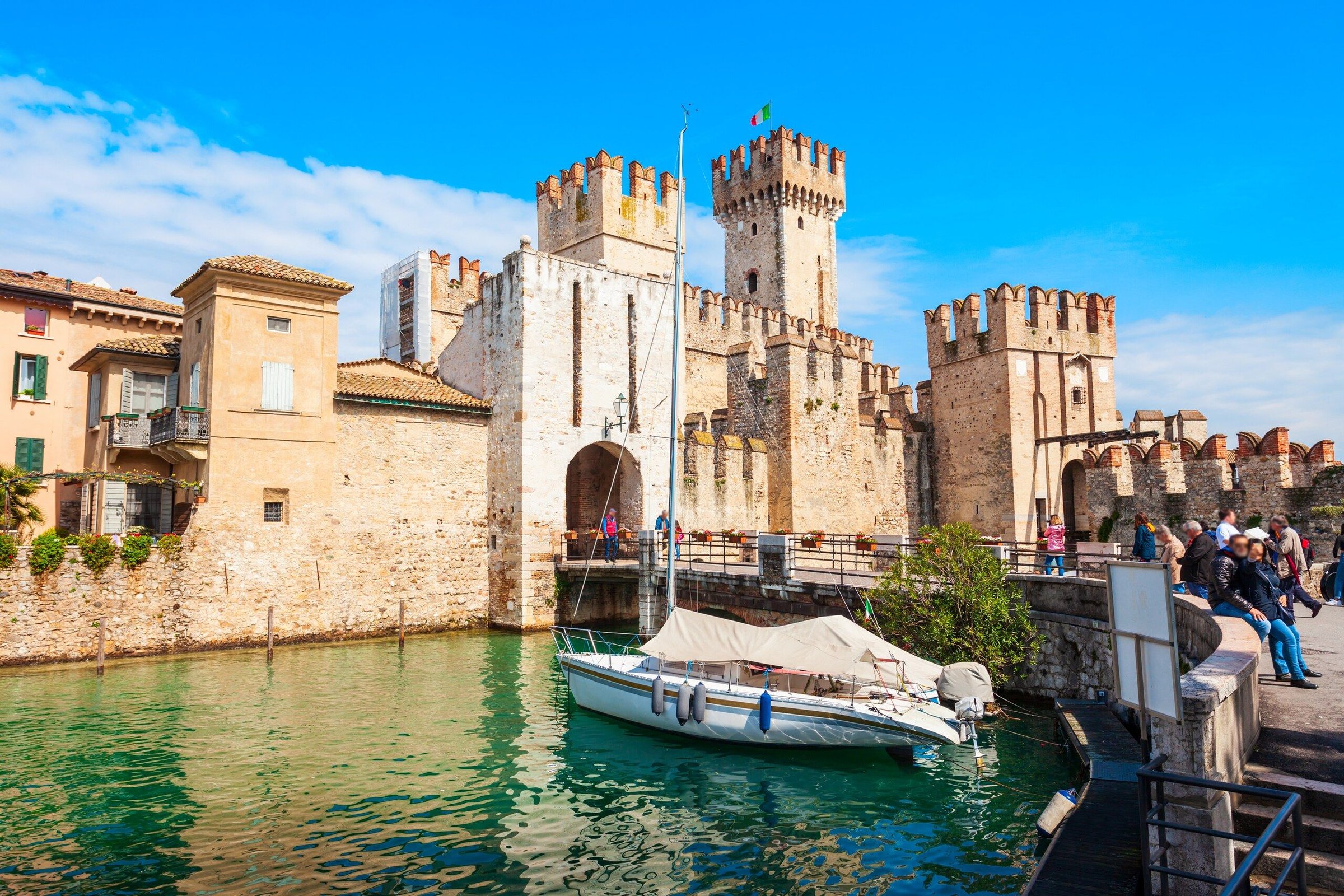 Kastil Scaligero di Sirmione dengan air danau yang hijau dan perahu kecil di dermaga.