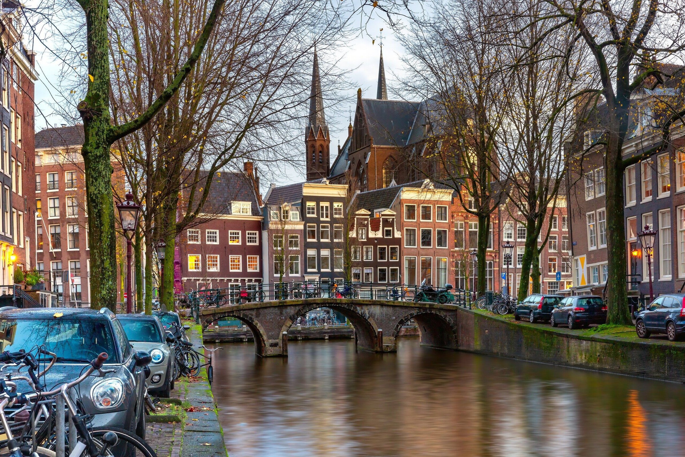 Kanal Leidsegracht Amsterdam dengan rumah khas Belanda, jembatan, dan pohon gundul di musim dingin.