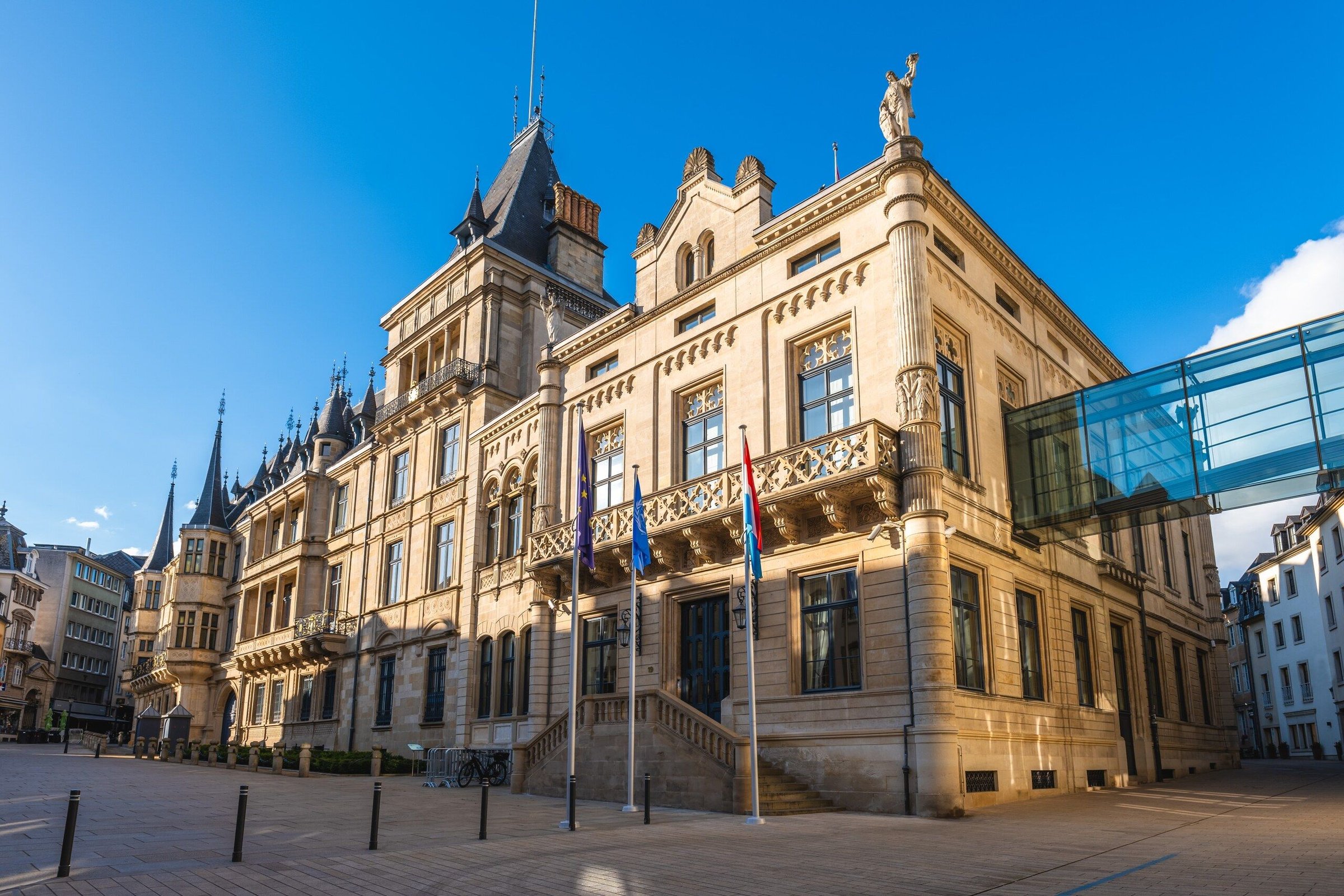 Gedung di dekat Grand Ducal Palace di Luxembourg dengan lorong kaca dan langit biru.