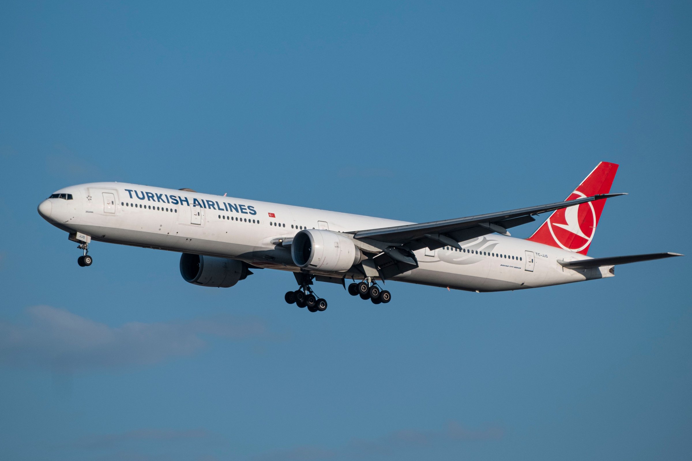 Pesawat Turkish Airlines Boeing 777 lepas landas dengan roda masih terbuka di langit biru cerah