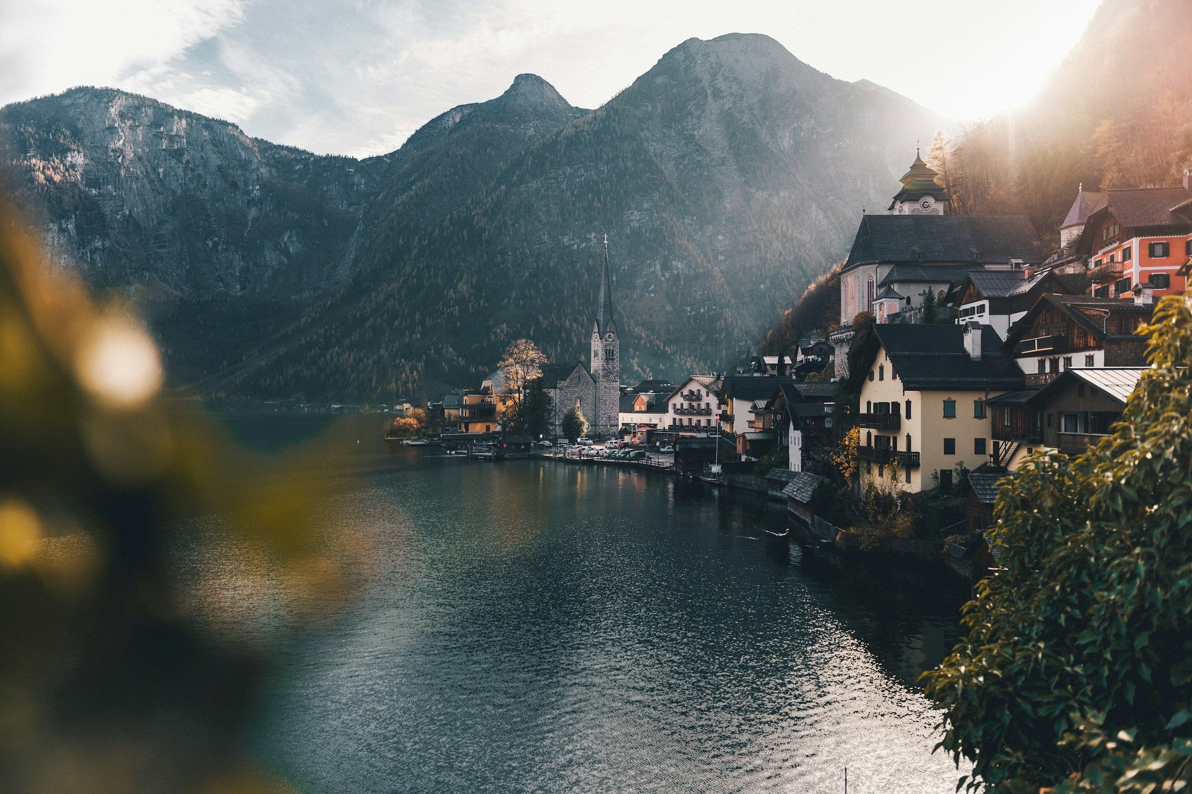 Desa Hallstatt di tepi danau dengan menara gereja dan pegunungan saat senja keemasan