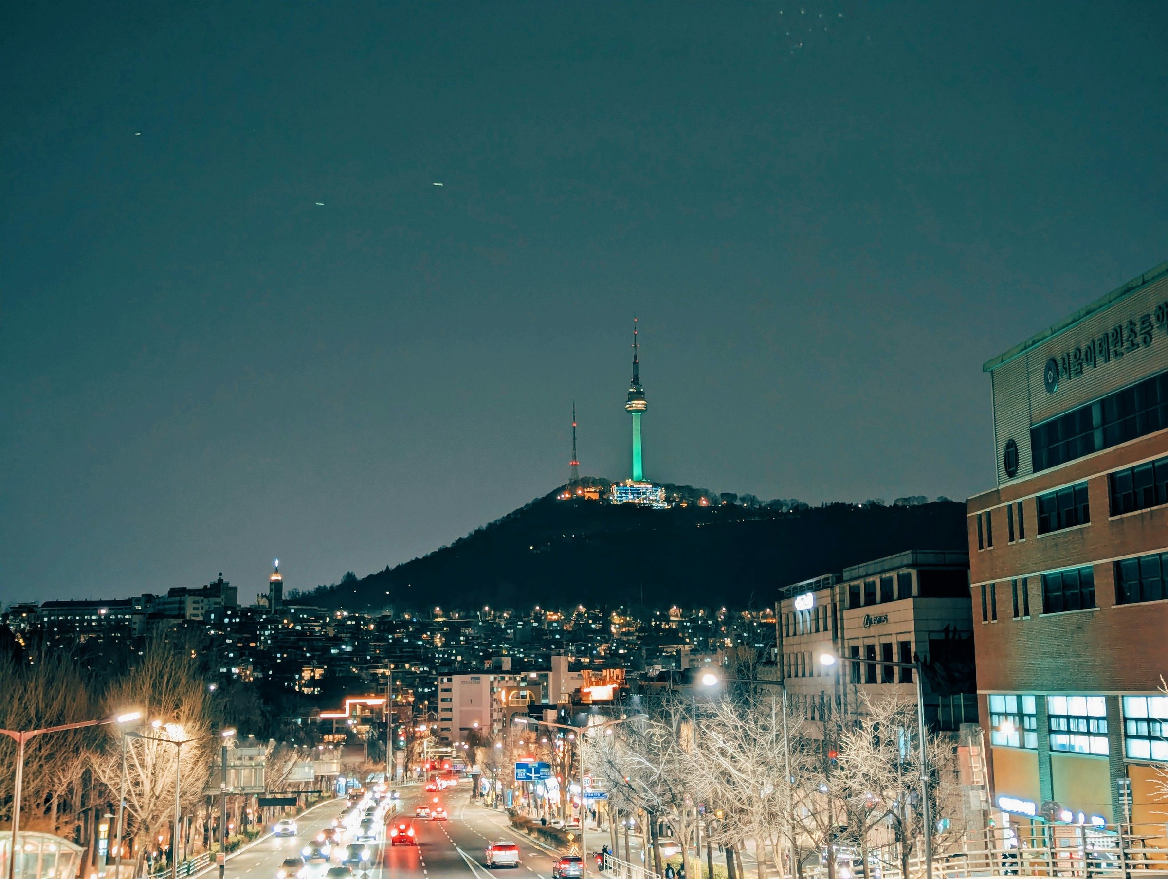 Kota Seoul berselimut salju dengan gedung dan bukit di kejauhan.