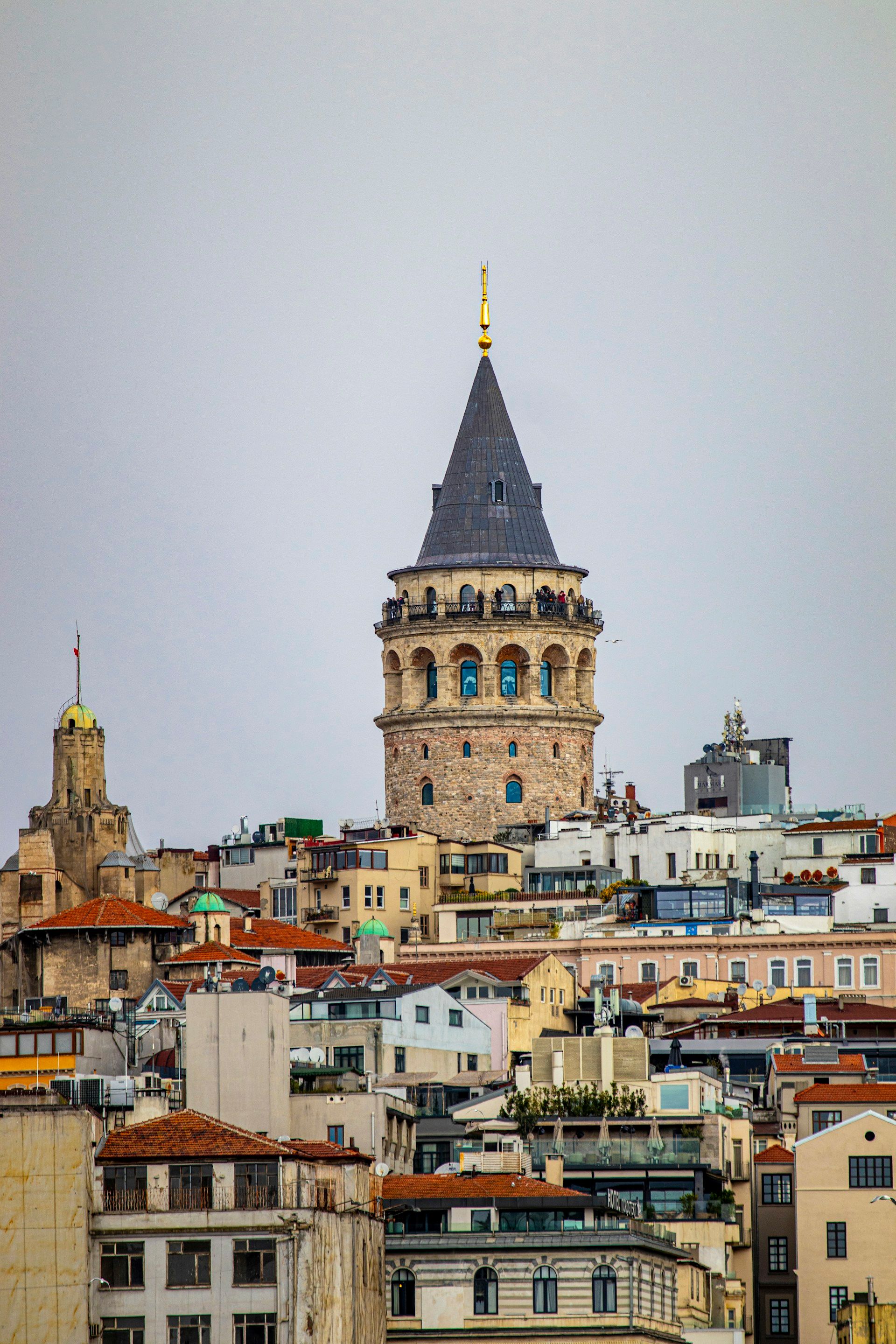 Menara Galata menjulang di atas atap-atap padat Beyoglu Istanbul, menara batu silindris bersejarah dengan atap kerucut khas