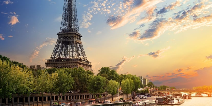 Kapal wisata menyusuri Sungai Seine dengan Menara Eiffel dan langit senja jingga