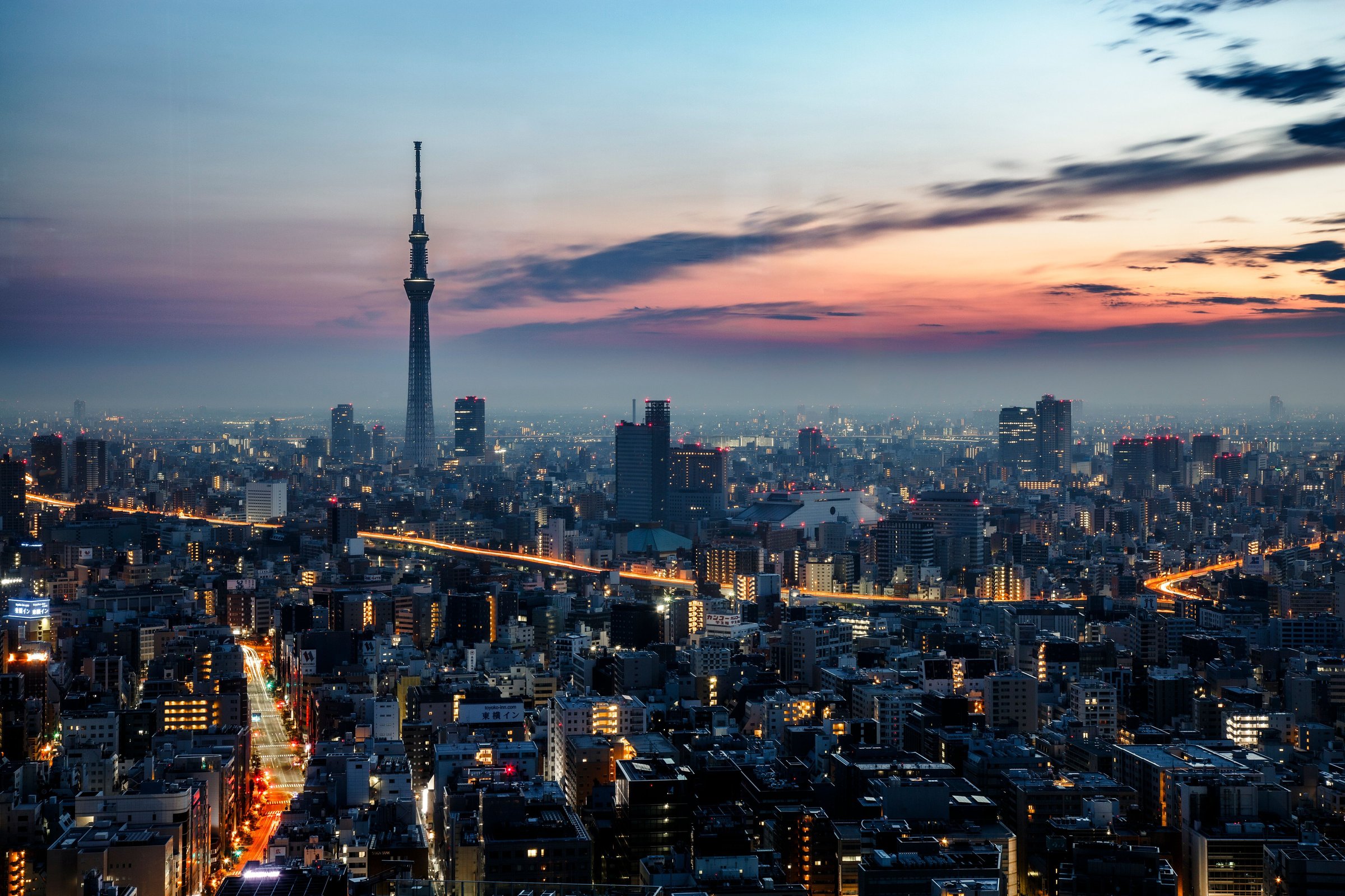Tokyo Skytree menjulang di atas skyline kota saat senja dengan langit jingga keunguan