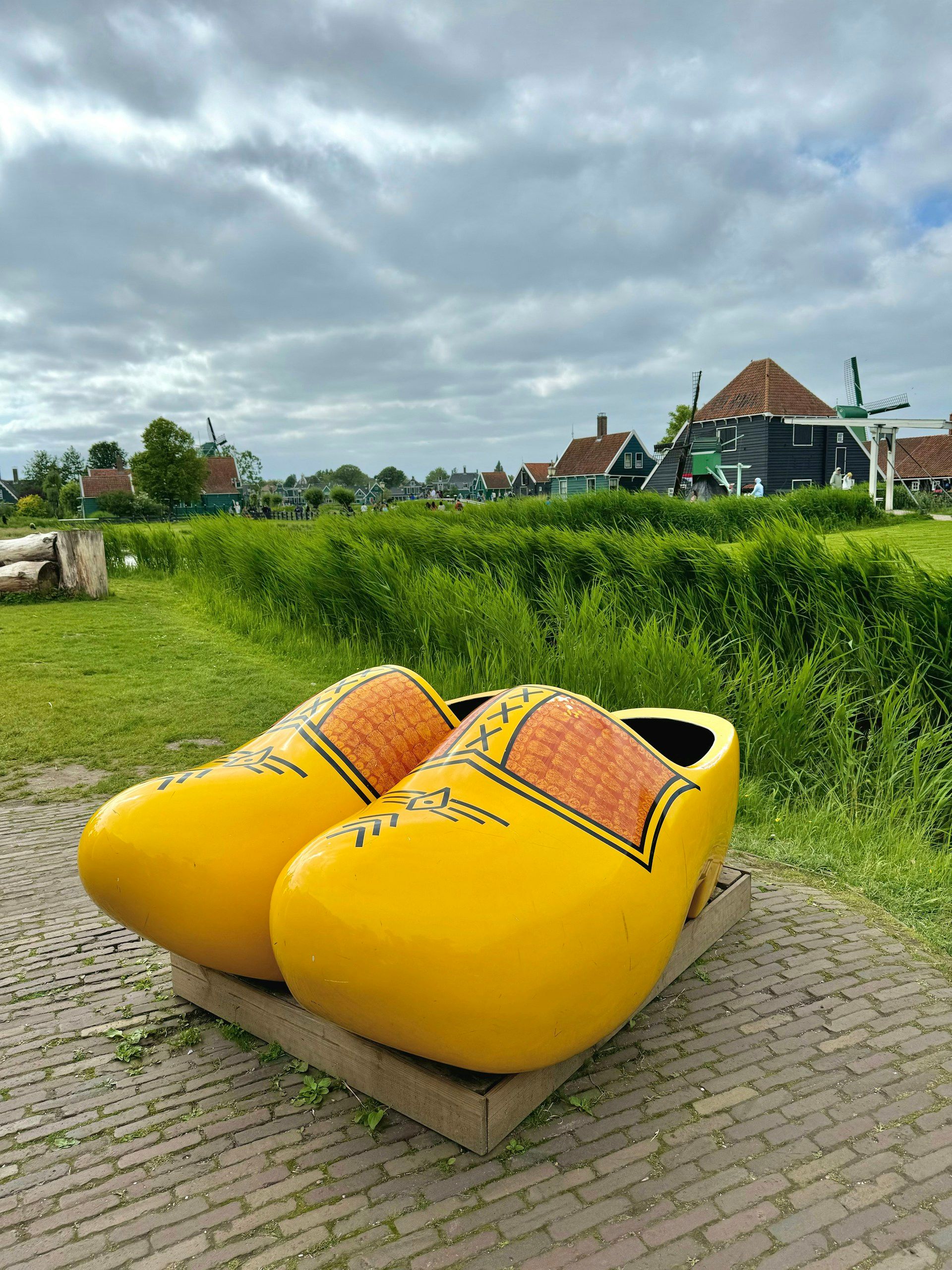 Klompen kayu raksasa di Zaanse Schans dengan kincir di latar
