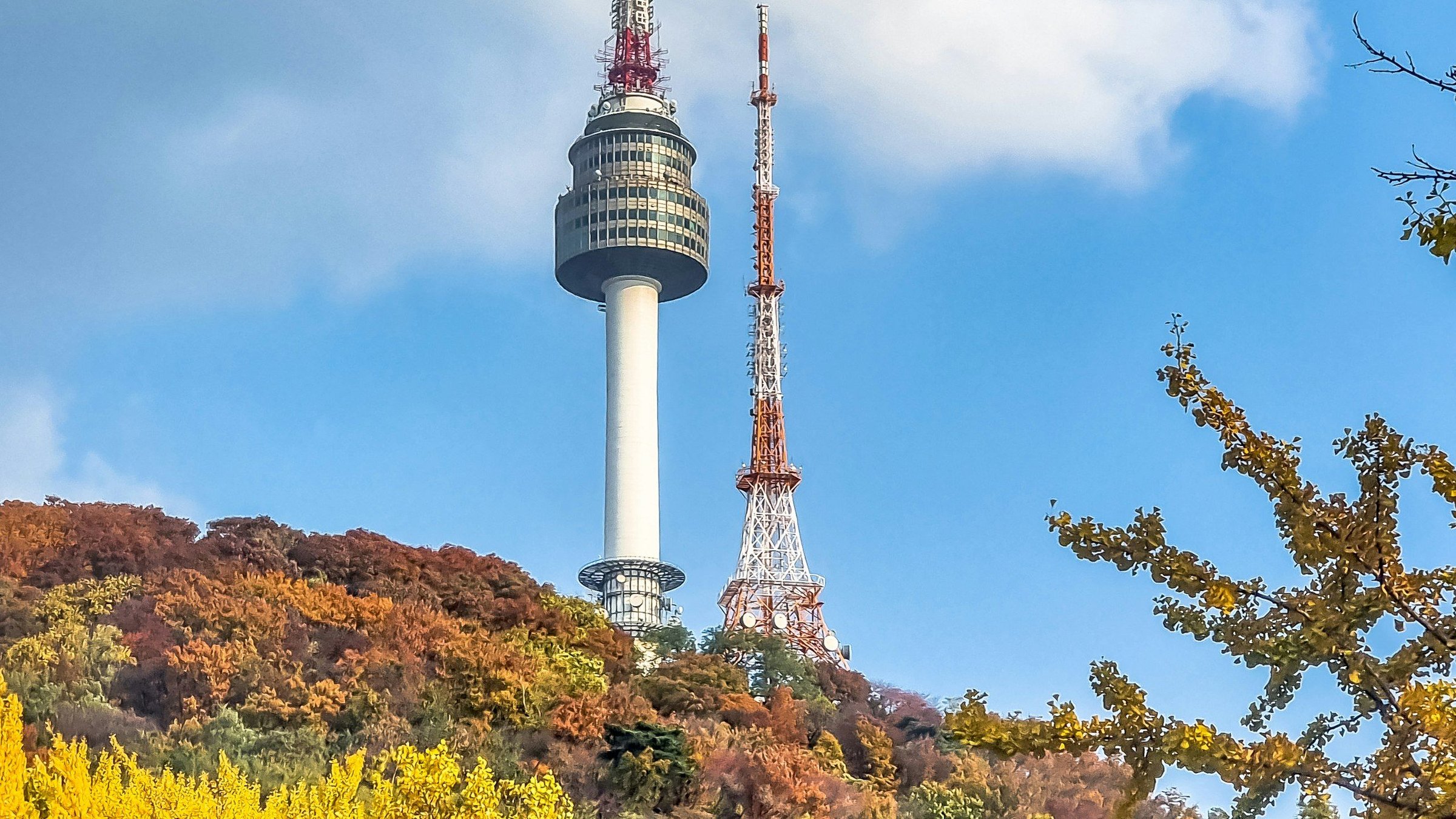 Menara N Seoul Namsan menjulang di atas bukit berdedaunan musim gugur merah, oranye, dan kuning ginkgo dengan langit biru cerah di Seoul, Korea