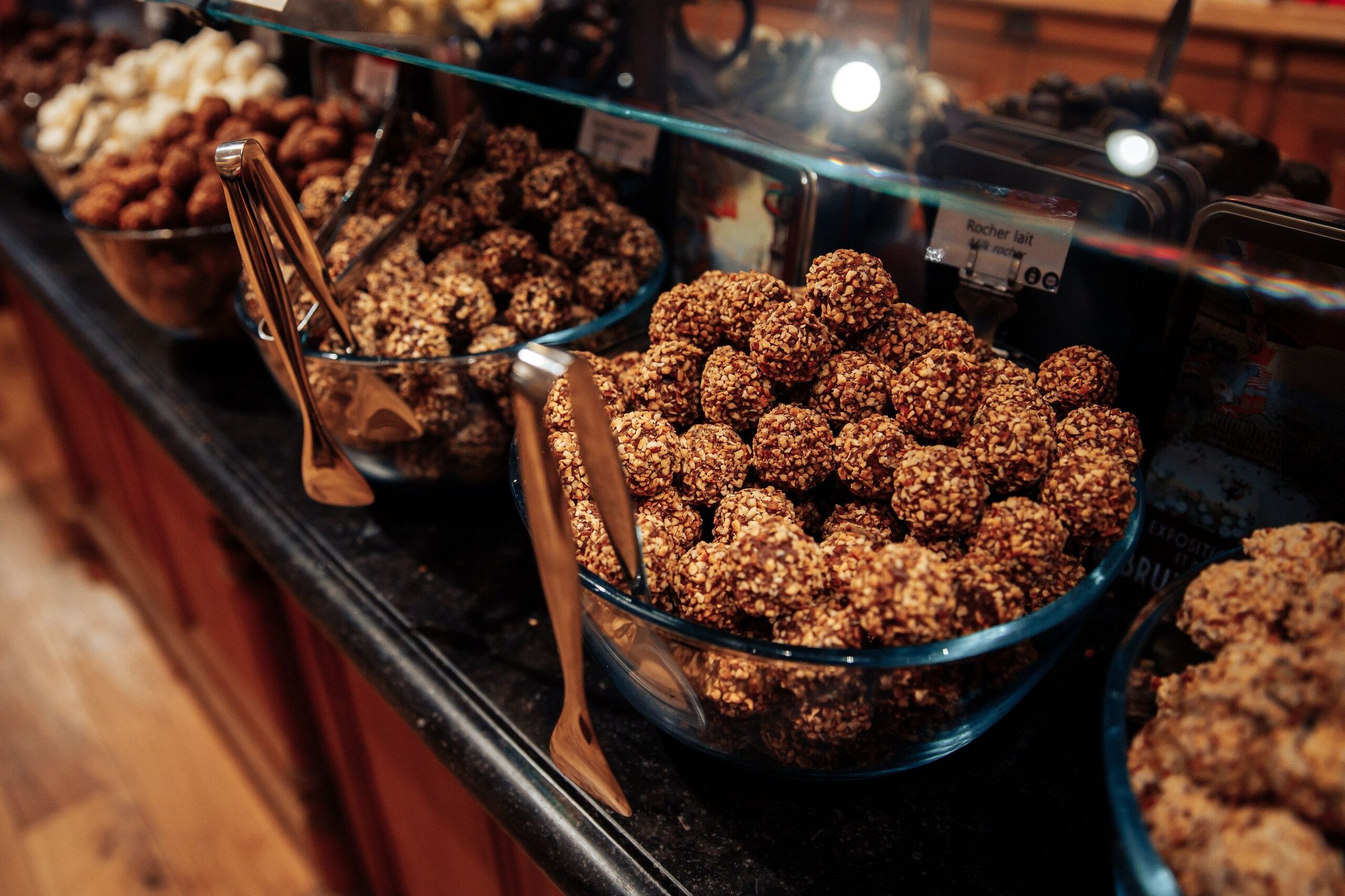 Cokelat dan kacang berlapis cokelat di etalase toko cokelat tradisional Brussels.