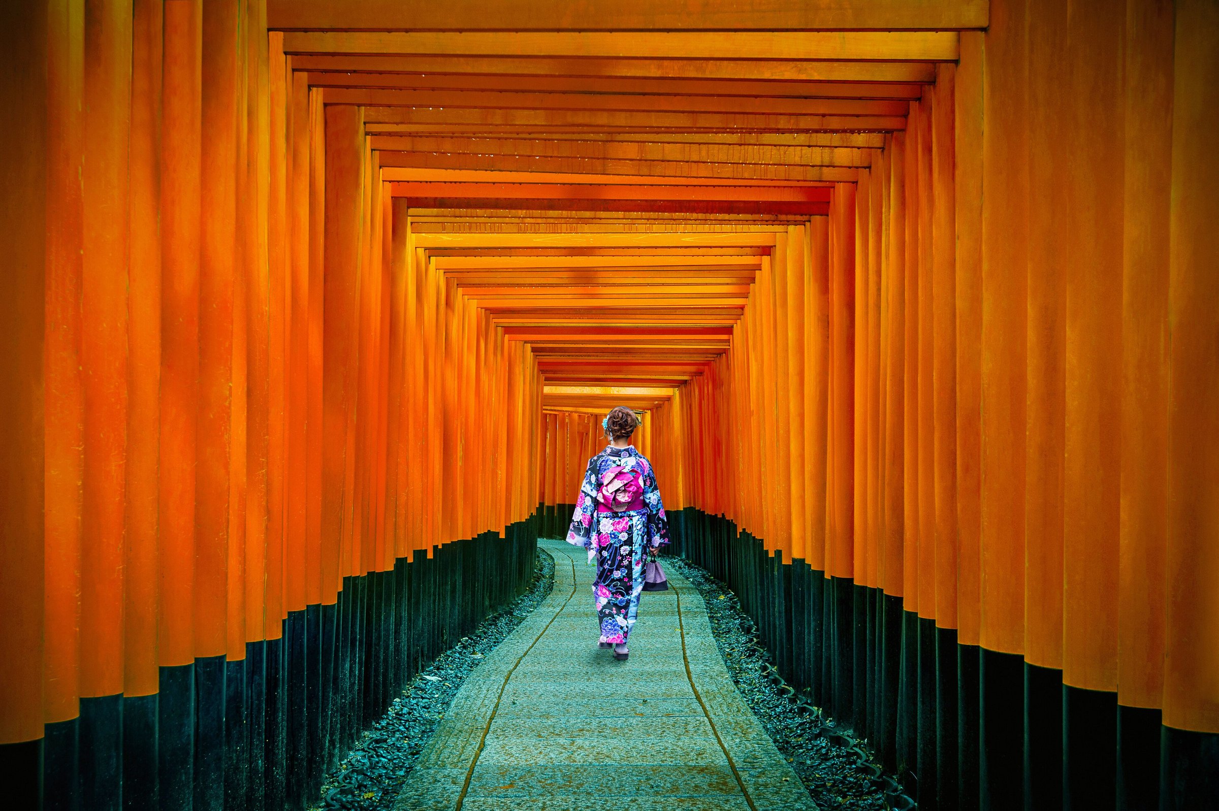 Perempuan berkimono berjalan di lorong ribuan gerbang torii merah di Fushimi Inari, Kyoto