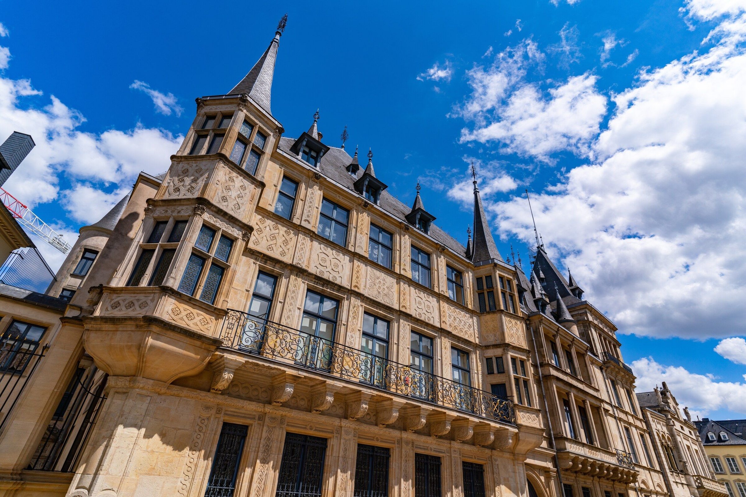 Fasad Grand Ducal Palace di Luxembourg dari sudut rendah di bawah langit biru berawan.