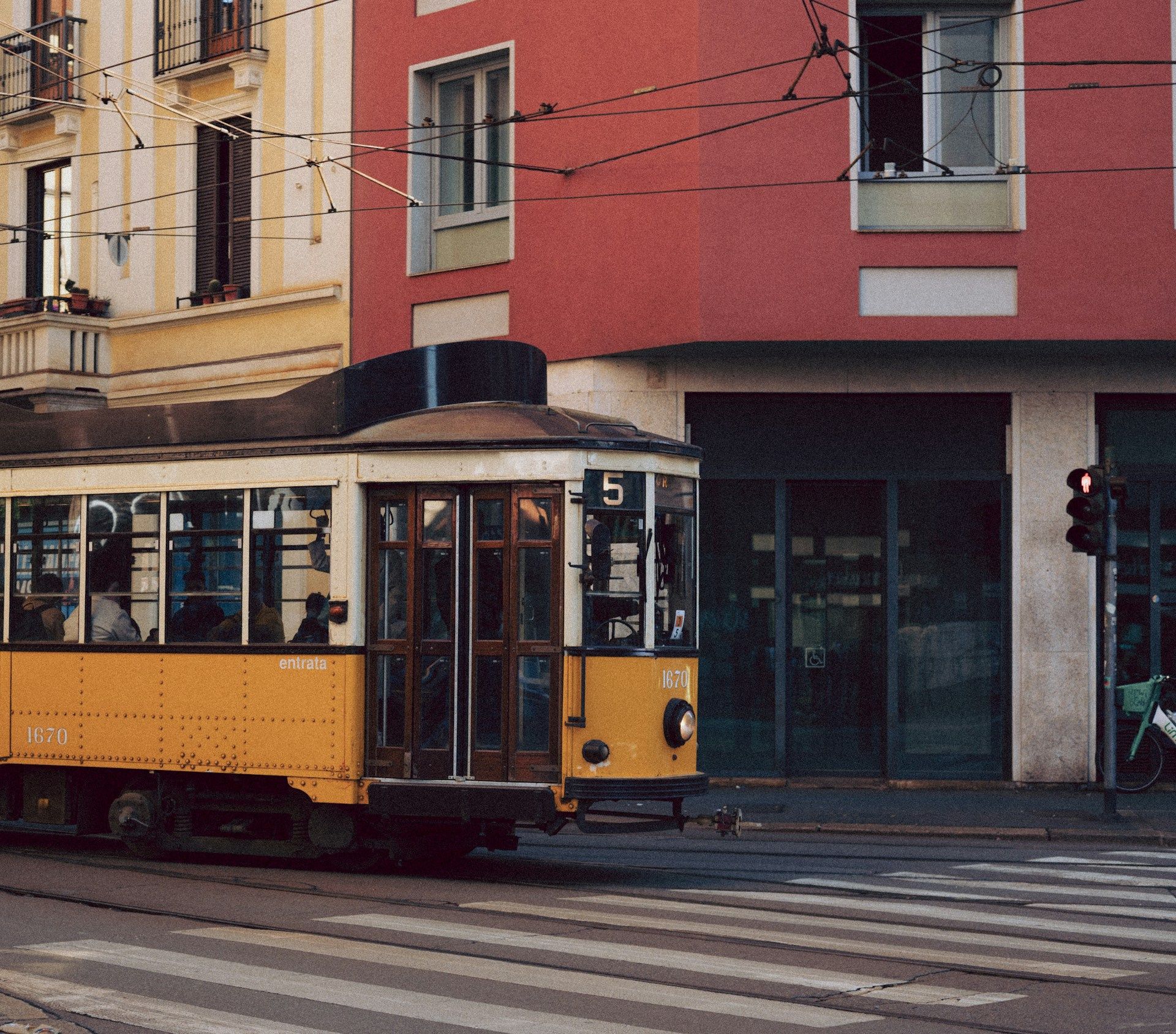 Trem kuning klasik Milan melintas di jalan kota, Italia