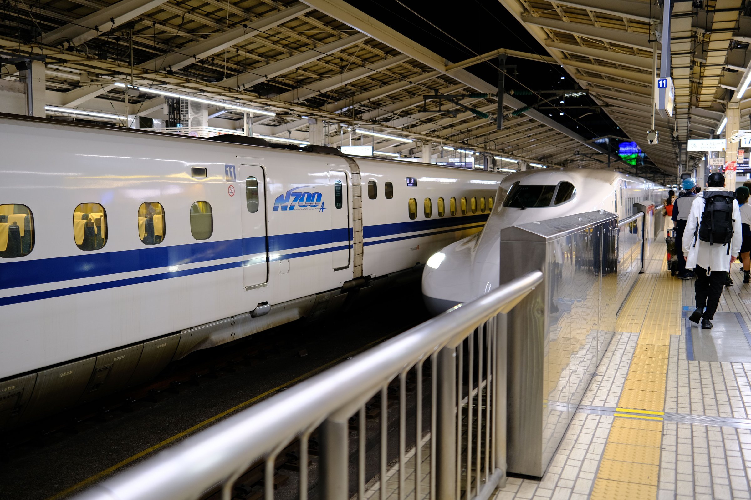 Kereta Shinkansen seri N700 putih bergaris biru berhenti di peron stasiun Jepang