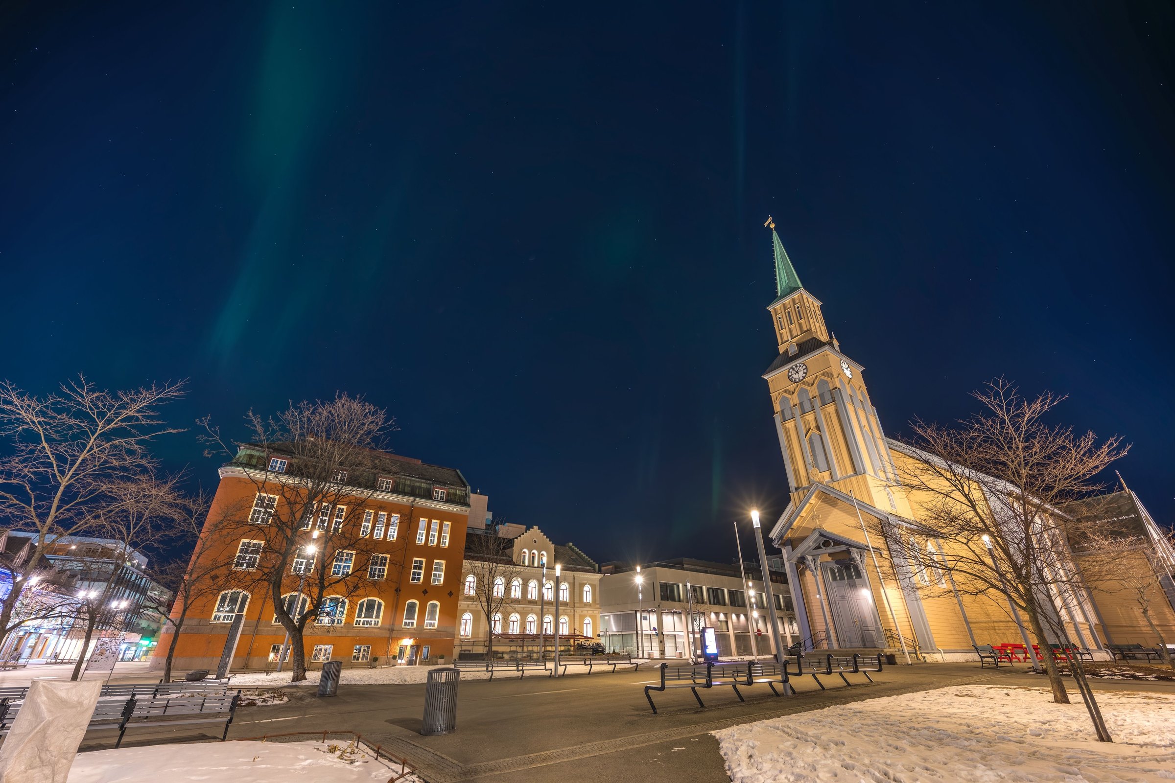 Tromso Domkirke, katedral kayu bergaya Gothic, di malam bersalju dengan cahaya utara samar di langit