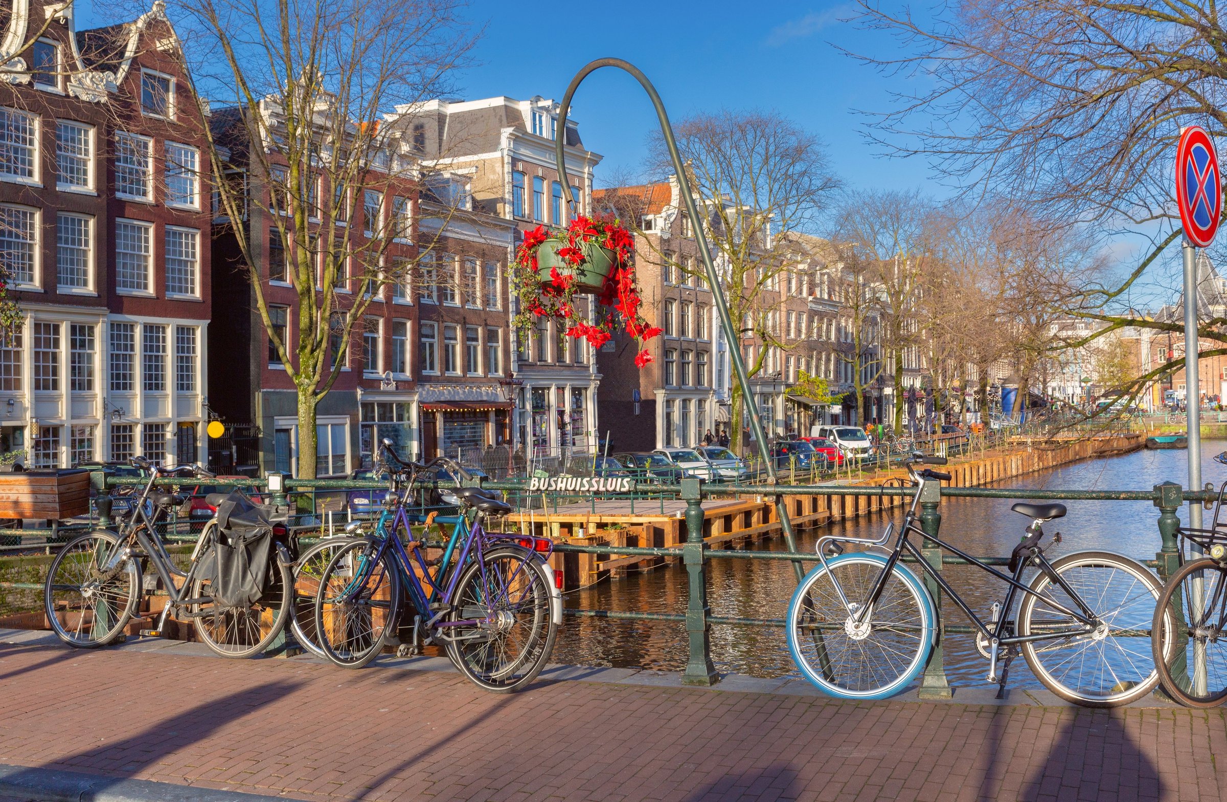 Rumah kanal Amsterdam bergaya gable berwarna-warni dengan deretan sepeda terparkir di pagar jembatan, Belanda